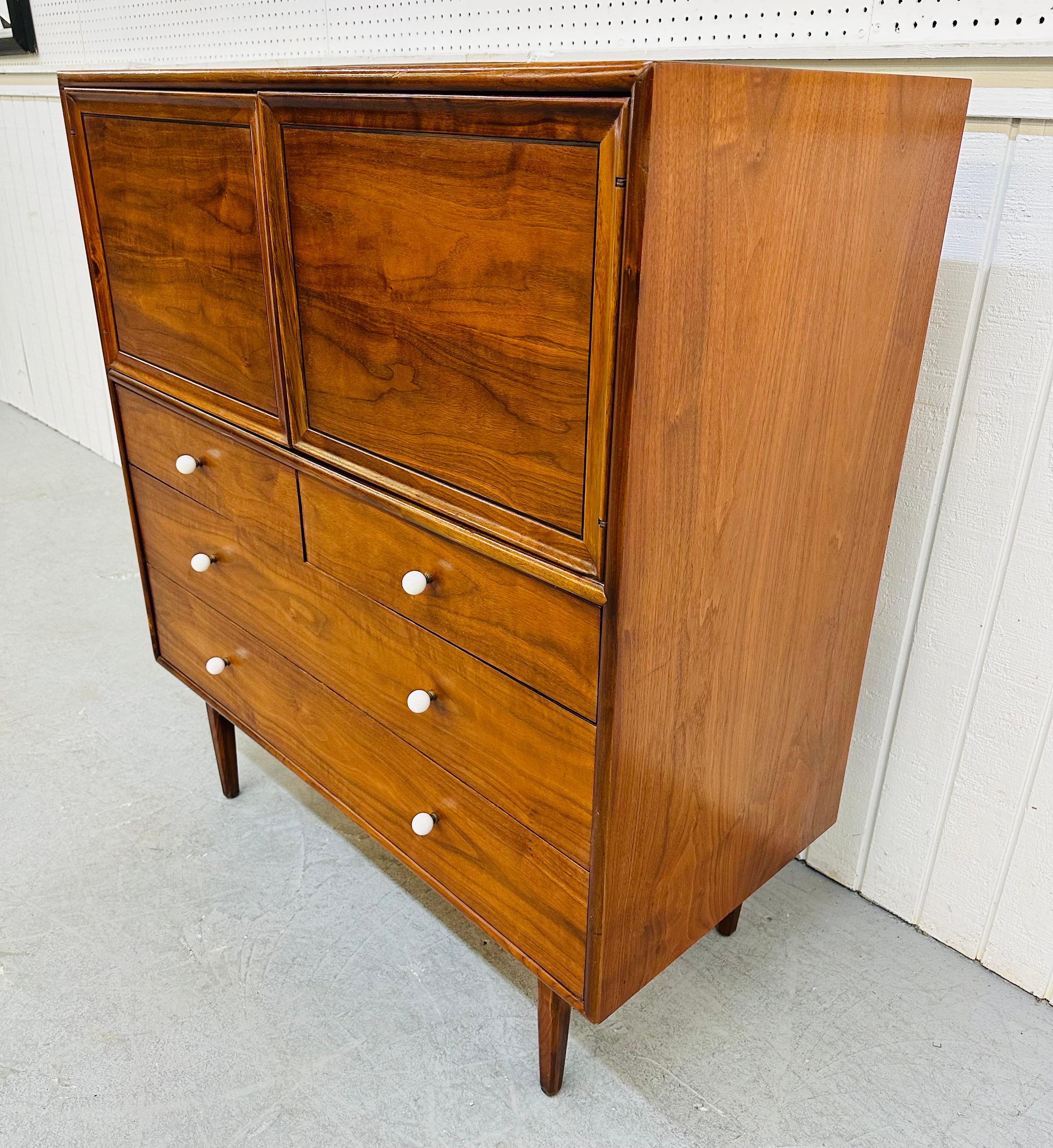 This listing is for a Mid-Century Modern Drexel declaration walnut high chest. Featuring a rectangular design, two doors up top that open up to three hidden drawers on the left, a hidden shaving mirror with storage space on the right, four drawers