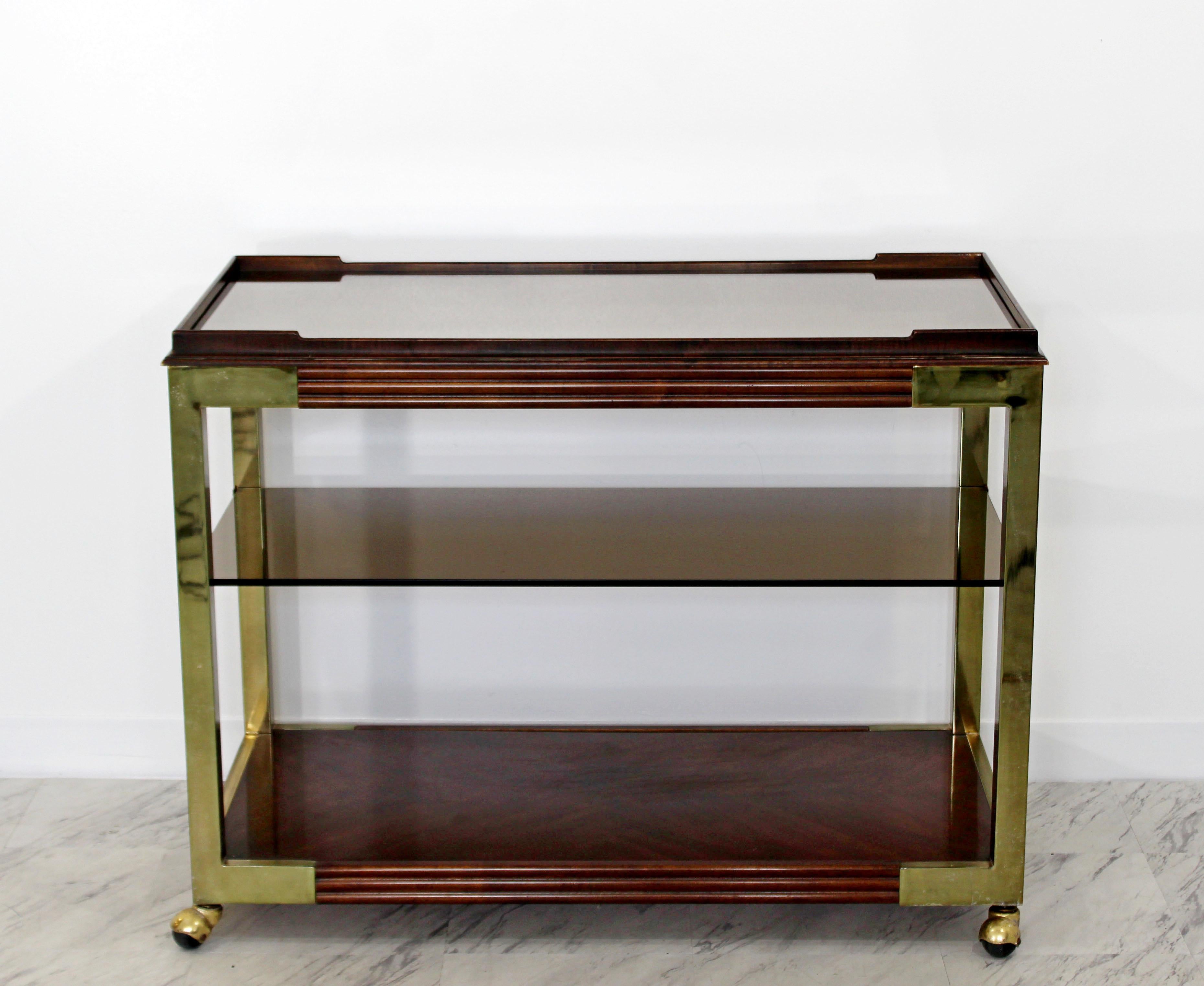 For your consideration is an incredible, two-tiered bar service cart, with a smoked glass shelf and a mirrored top shelf and brass accents, by Drexel Heritage, circa 1950s-1960s. In great condition. The dimensions are 40.5