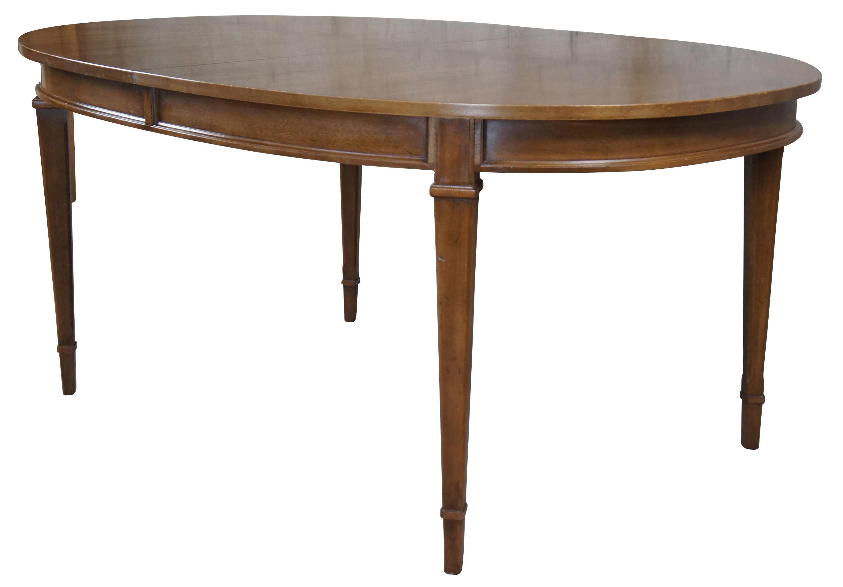 Vintage Drexel Triune dining table. Made of mahogany featuring an oval form, inset panel apron and square tapered legs. Includes 3 table leaf's. circa 1968. 555-333-5.

Dimensions:

44