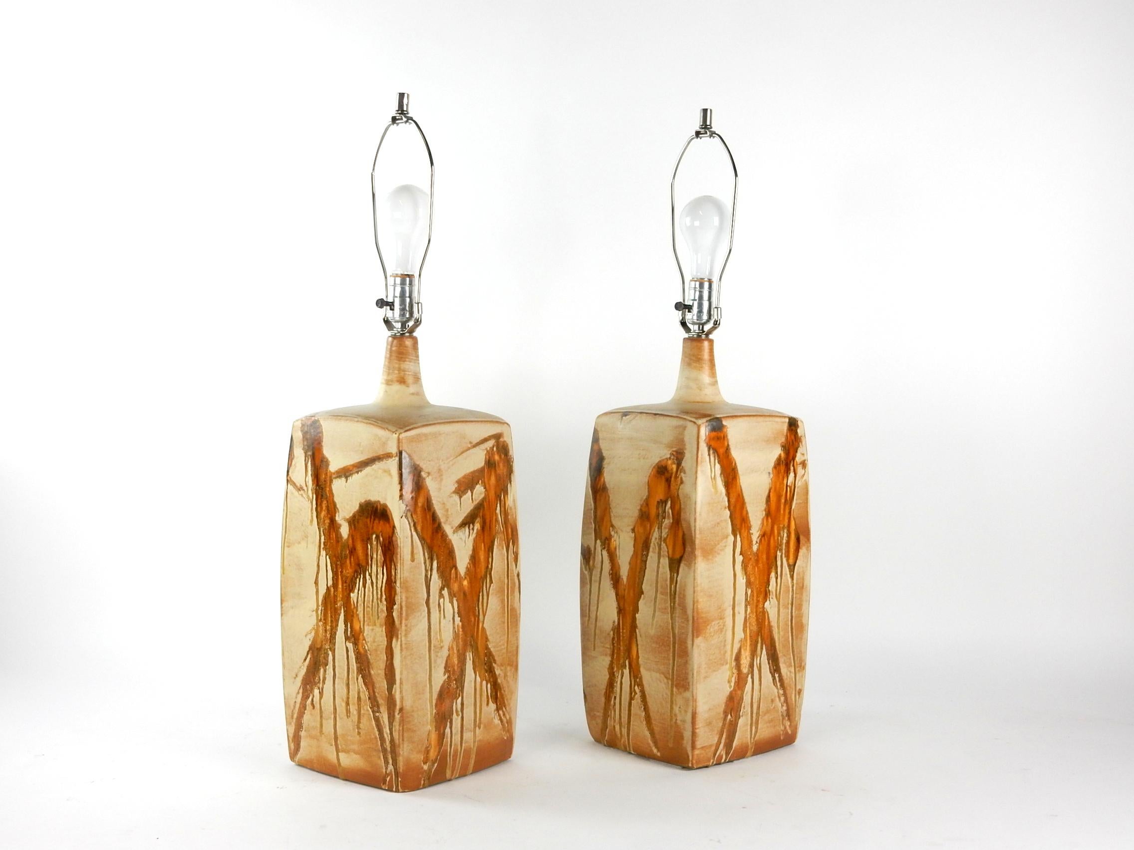 A pair of large boxy shape ceramic table lamps from the Mid-Century Modern era.
Each with crisscrossing diagonal splashes of caramel and ochre drip glaze over a brown earth tone.
All original with UL wiring and hardware.
The ceramic body of lamps
