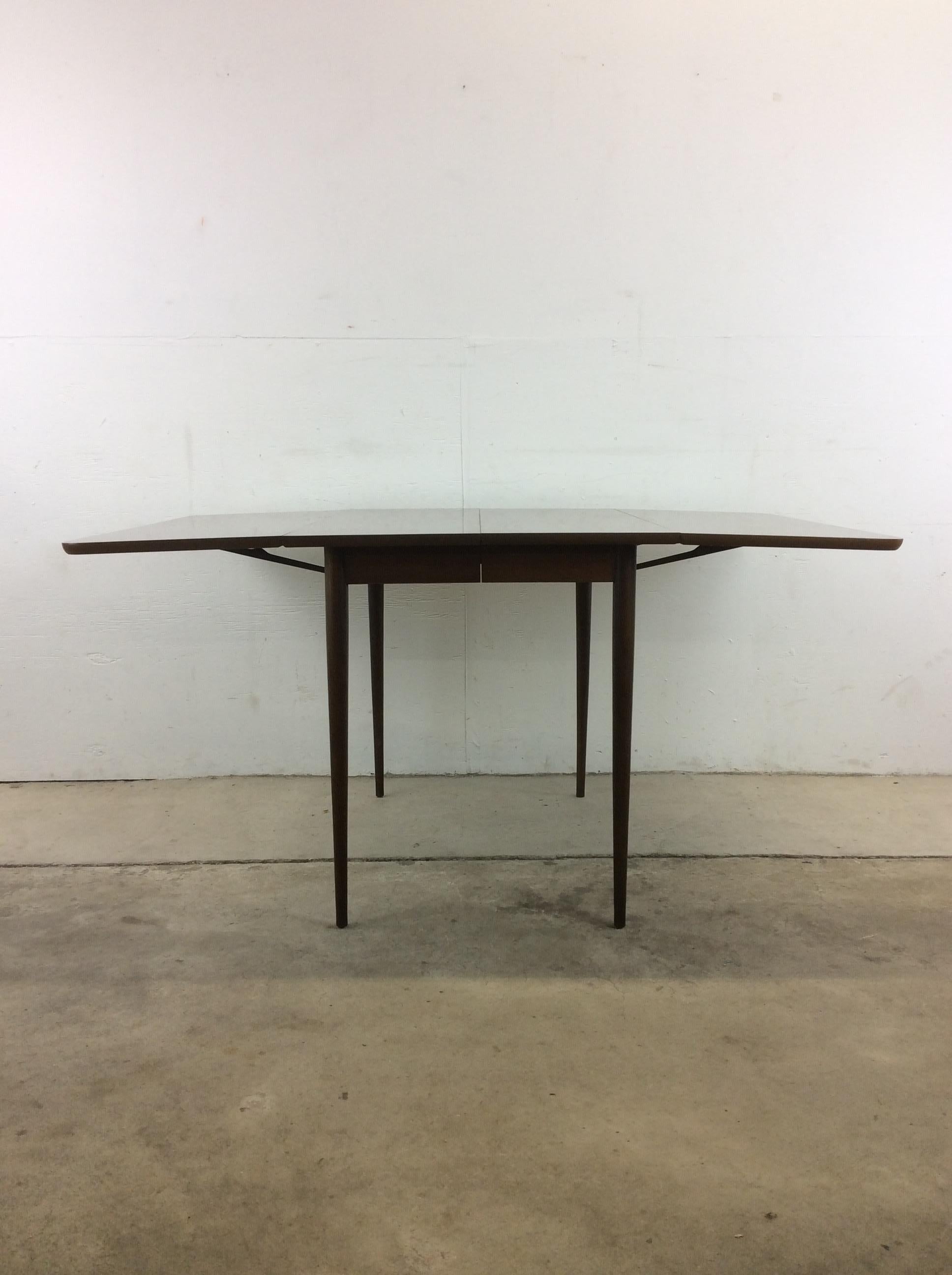 This Mid-Century Modern dining table features drop leaf design, durable formica top with faux woodgrain, two additional leafs, and tall tapered legs.??Complimentary dining chairs available separately. 

Dimensions: 59.5w 40d 30.25h + 3 12w leafs