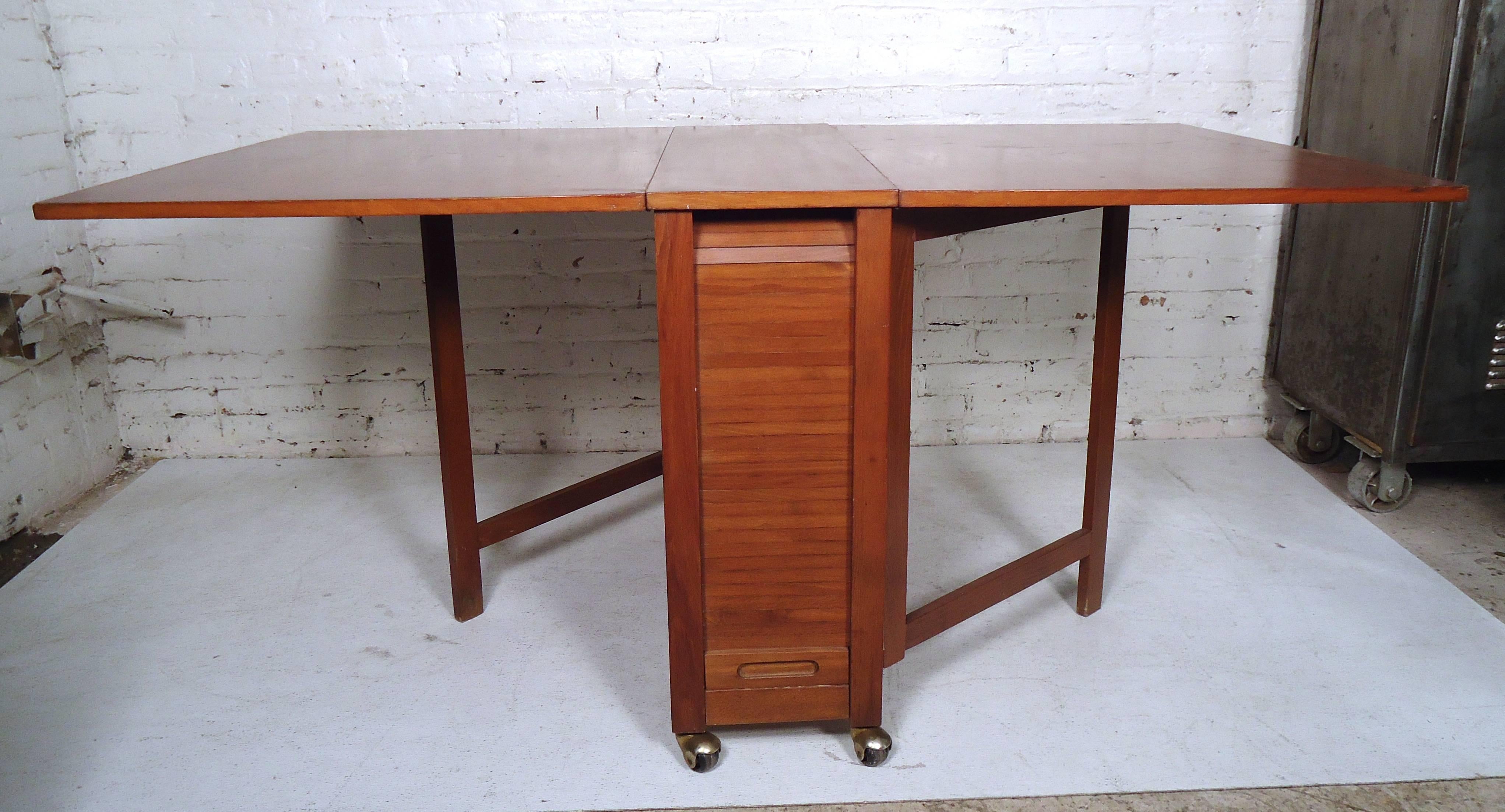 Impressive vintage modern compact design with four unique folding chairs and a drop-leaf dining table.
Sleek design offers the ability to stow all four chairs within the table hidden behind a tambour door. Sturdy and stylish piece with gate legs