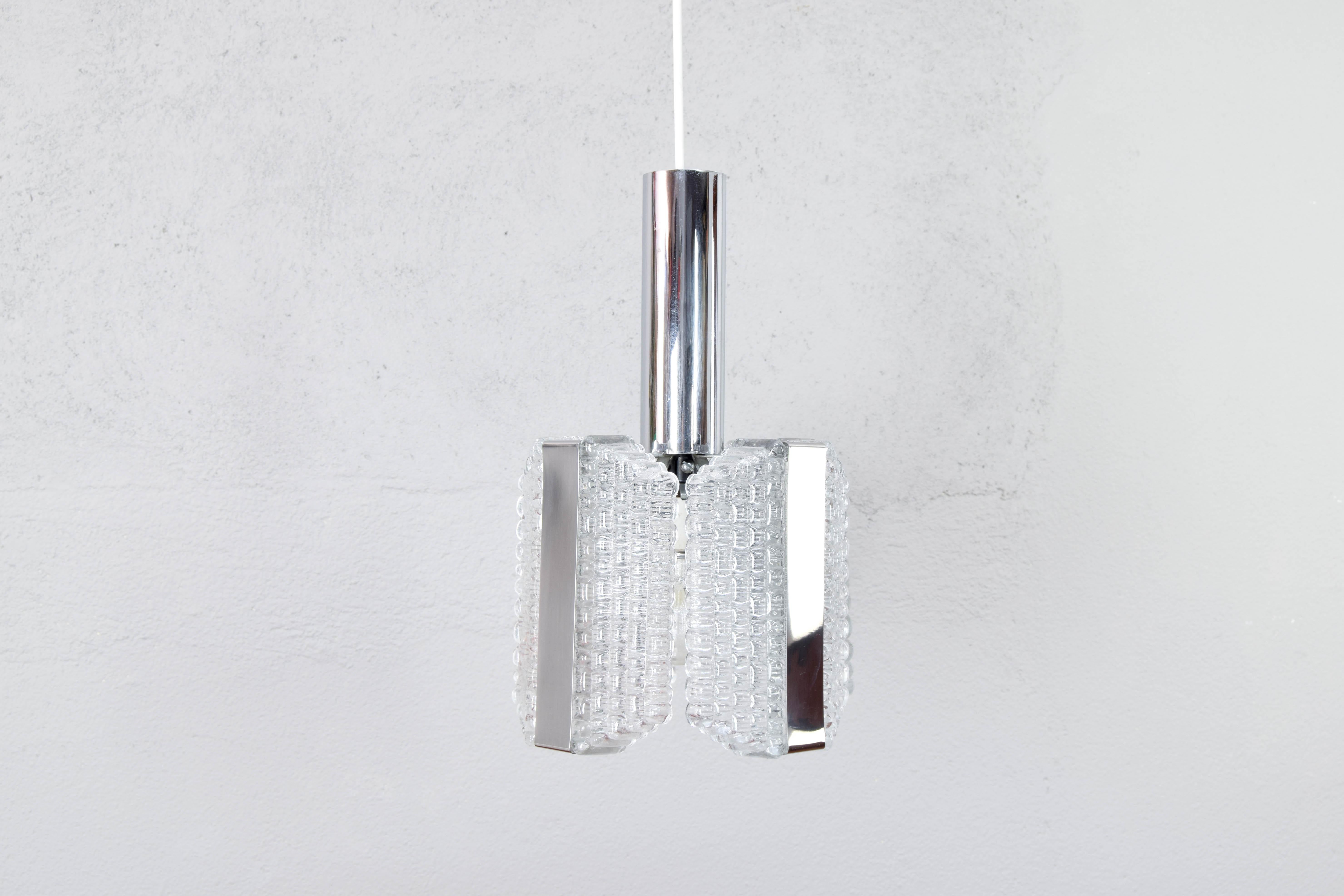 Mid-Century Modern Chandelier designed and produced by Kaiser Leuchen in the 1960s.
Beautiful piece made up of a chromed steel body and four large octagonal blocks of textured glass and chromed steel bands.
This hanging lamp combines character and