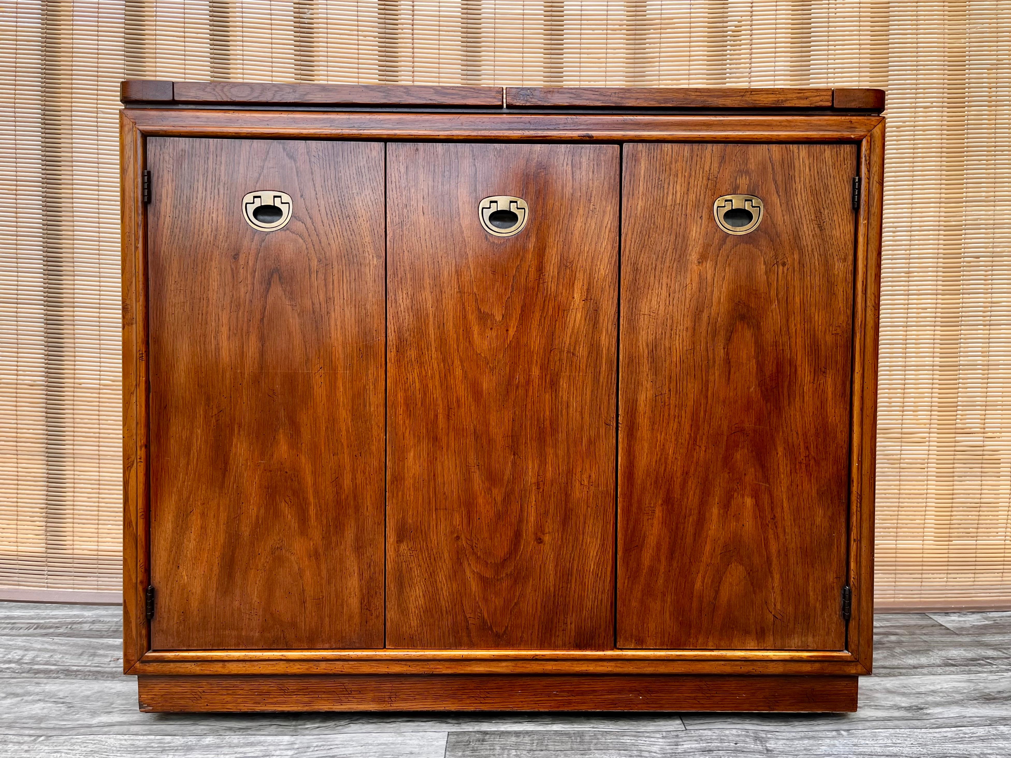 Buffet vintage Mid-Century Modern / Hollywood Regency / dry bar / server di drexel furniture, circa 1960.
Presenta un piano apribile con un'area di servizio in laminato nero, una bellissima venatura del legno, maniglie in ottone, un sacco di spazio