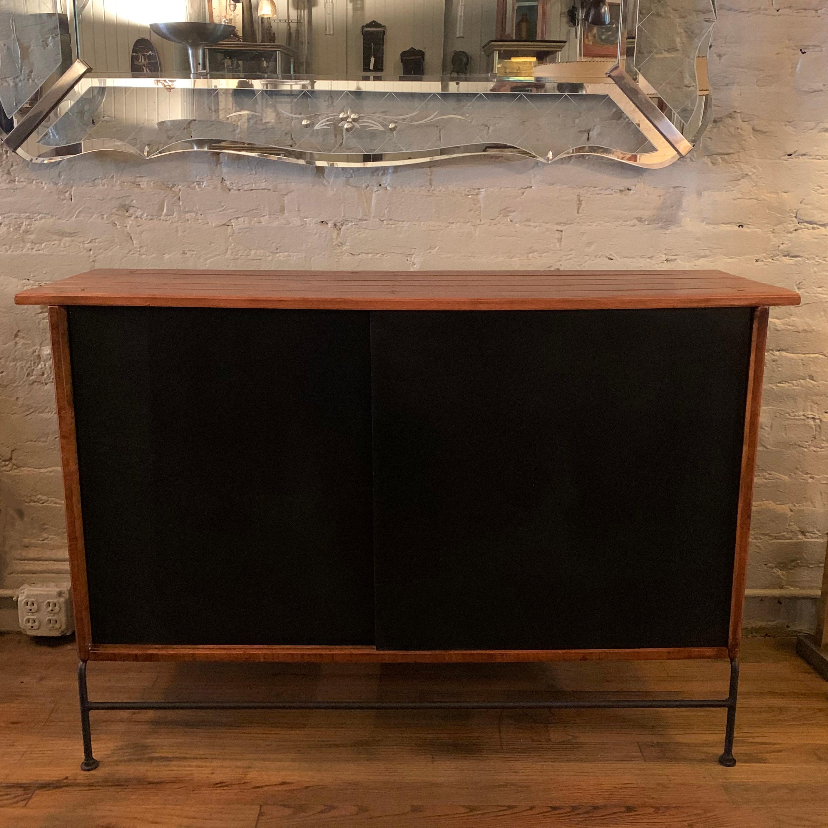 Mid-Century Modern, sideboard, dry bar by Arthur Umanoff features a slat maple surround with black sliding doors on a wrought iron base. Perfect as a shallow sideboard or bar cabinet.