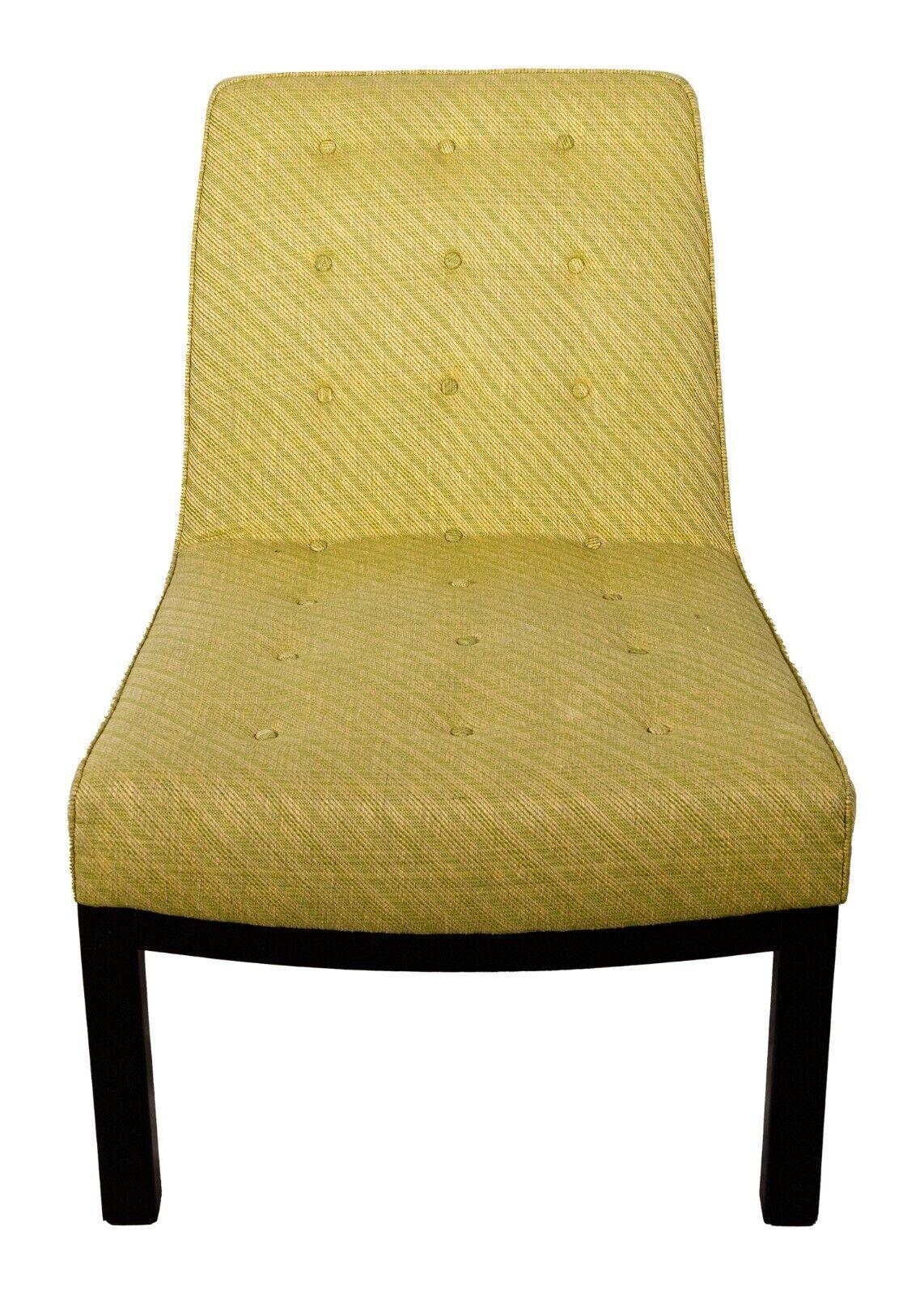 A Dunbar slipper chair. This is a very delightful chair from furniture brand Dunbar. This slipper chair features a green upholstery construction with rows of three buttons going up and down the seat and back of the chair. This piece features a