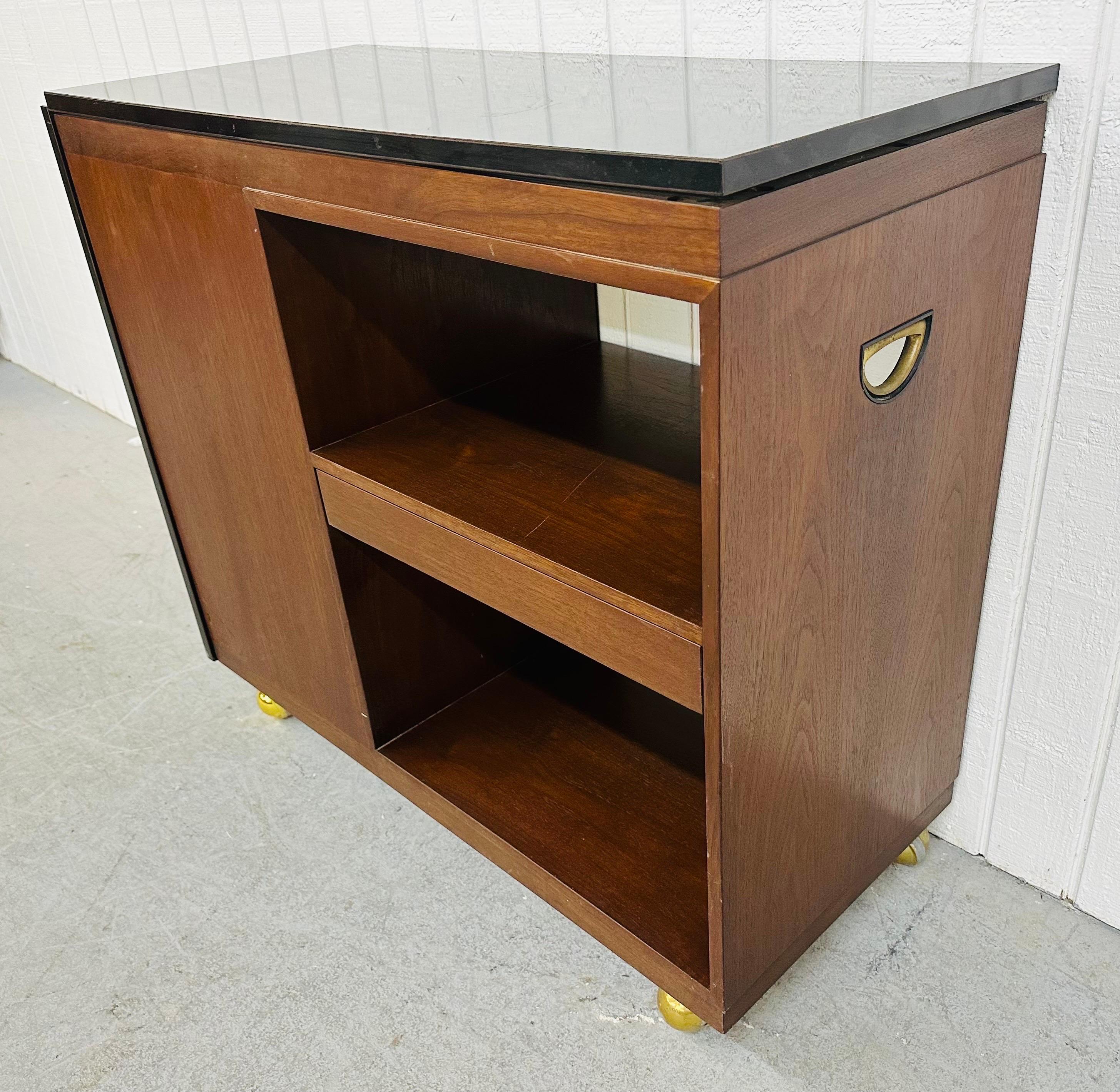 This listing is for a Mid-Century Modern Dunbar Walnut Bar Cart. Featuring a straight line design, expandable top, storage compartments, sliding drawer, original wheels for easy rolling, and a beautiful walnut finish. This is an exceptional