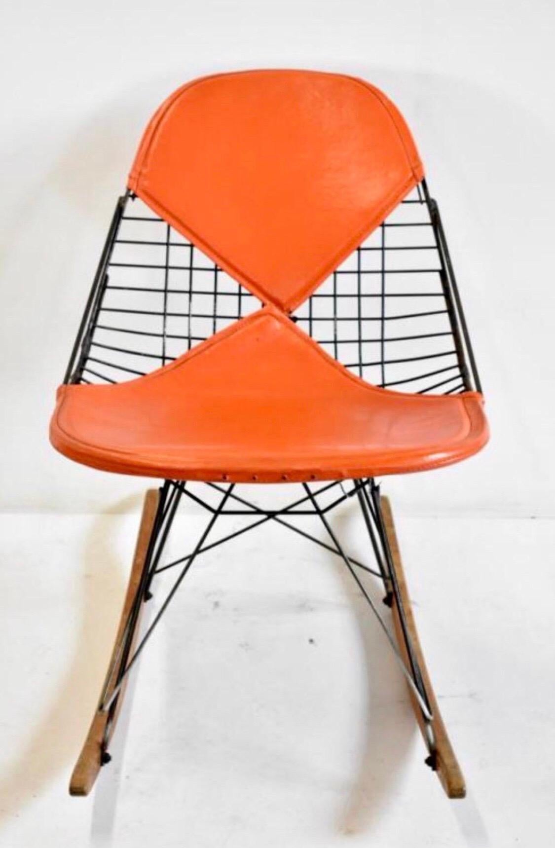Mid-Century Modern Eames RKR wire rocking chair features orange bikini pads for Herman Miller. Measures 27