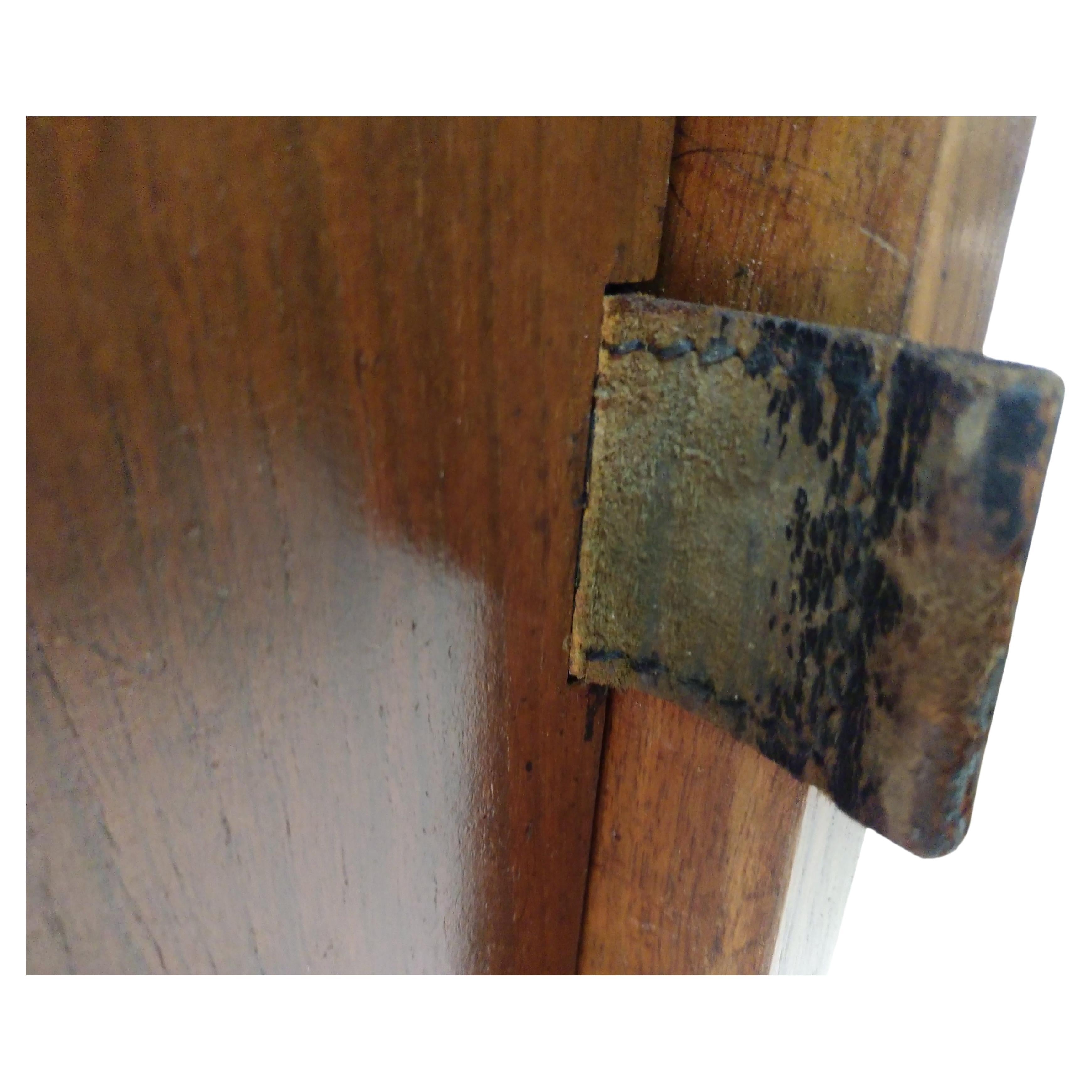 Diminutive credenza from the early 1950s. Walnut top is new veneer replacing worn Formica. Leather pulls a signature Florence Knoll design mark. Two sliding doors open to reveal two shelves. Painted steel legs.