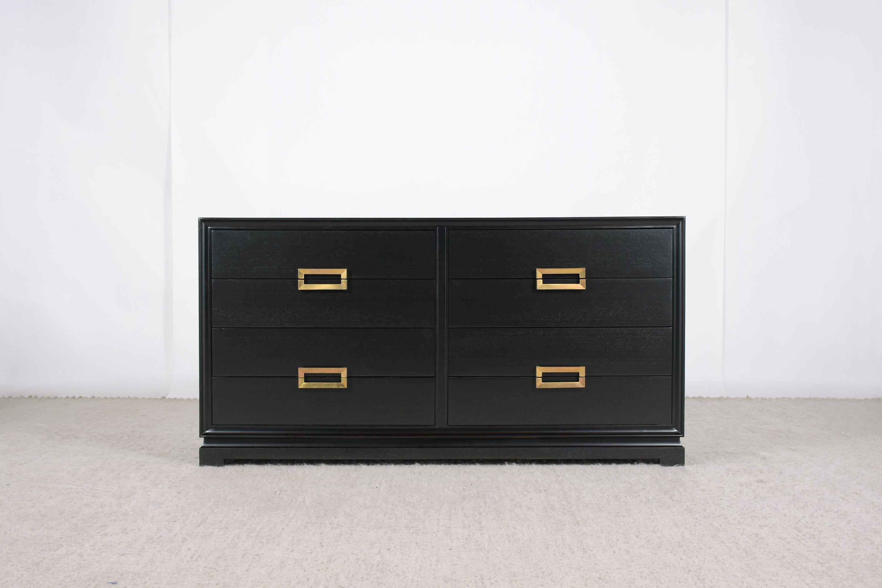 A 1960s Mid-Century Modern dresser is handcrafted out of mahogany wood with a newly ebonized lacquered satin finish and has been newly restored by our team of expert craftsmen. The chest comes with eight-drawers, eye-catching brass handles the chest