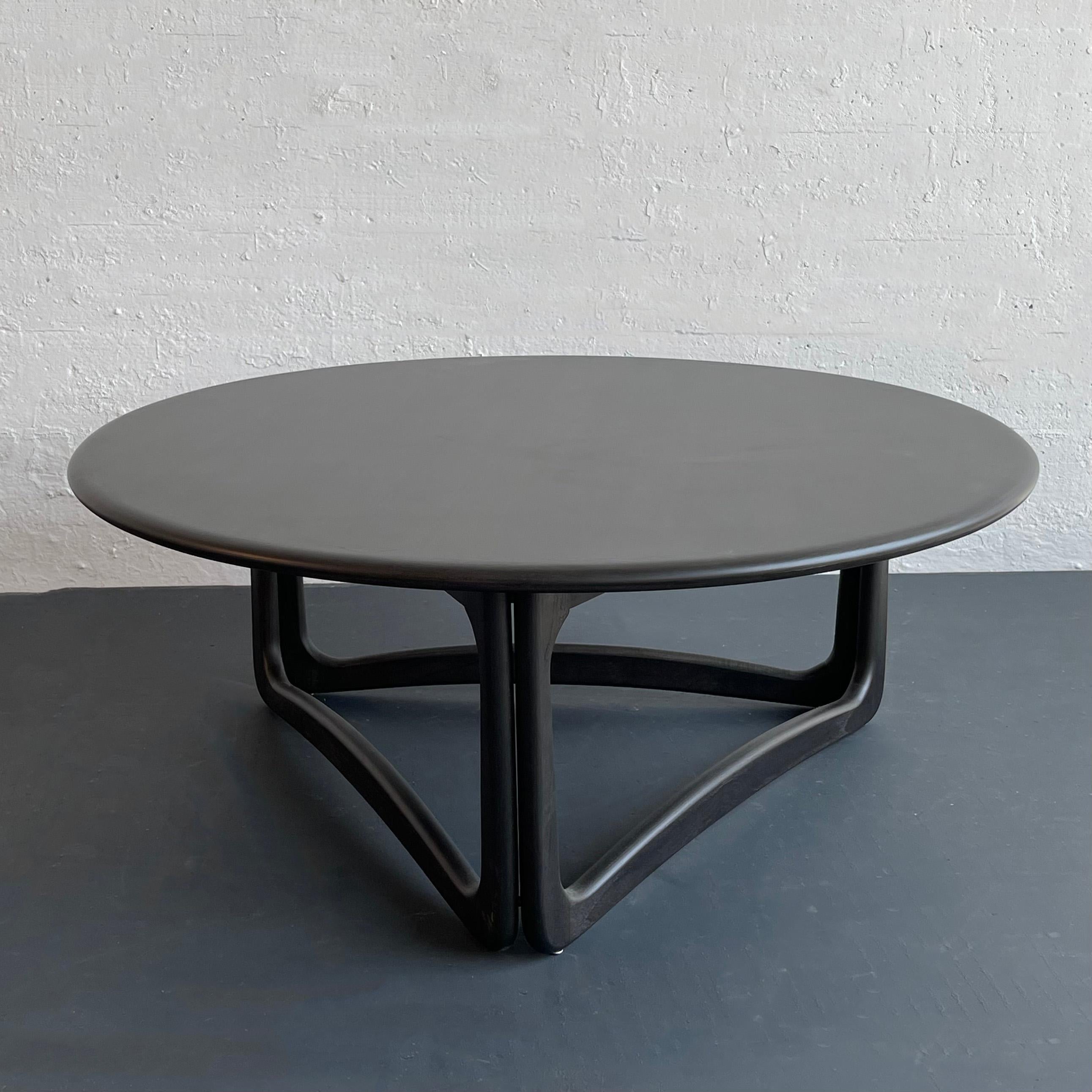 Mid-century modern round, ebonized oak coffee table with walnut trim designed by Warren C Church for Lane Furniture features an organically shaped, 3-leg, sculptural cutout base. 

The American Furniture company Lane Furniture was founded by John