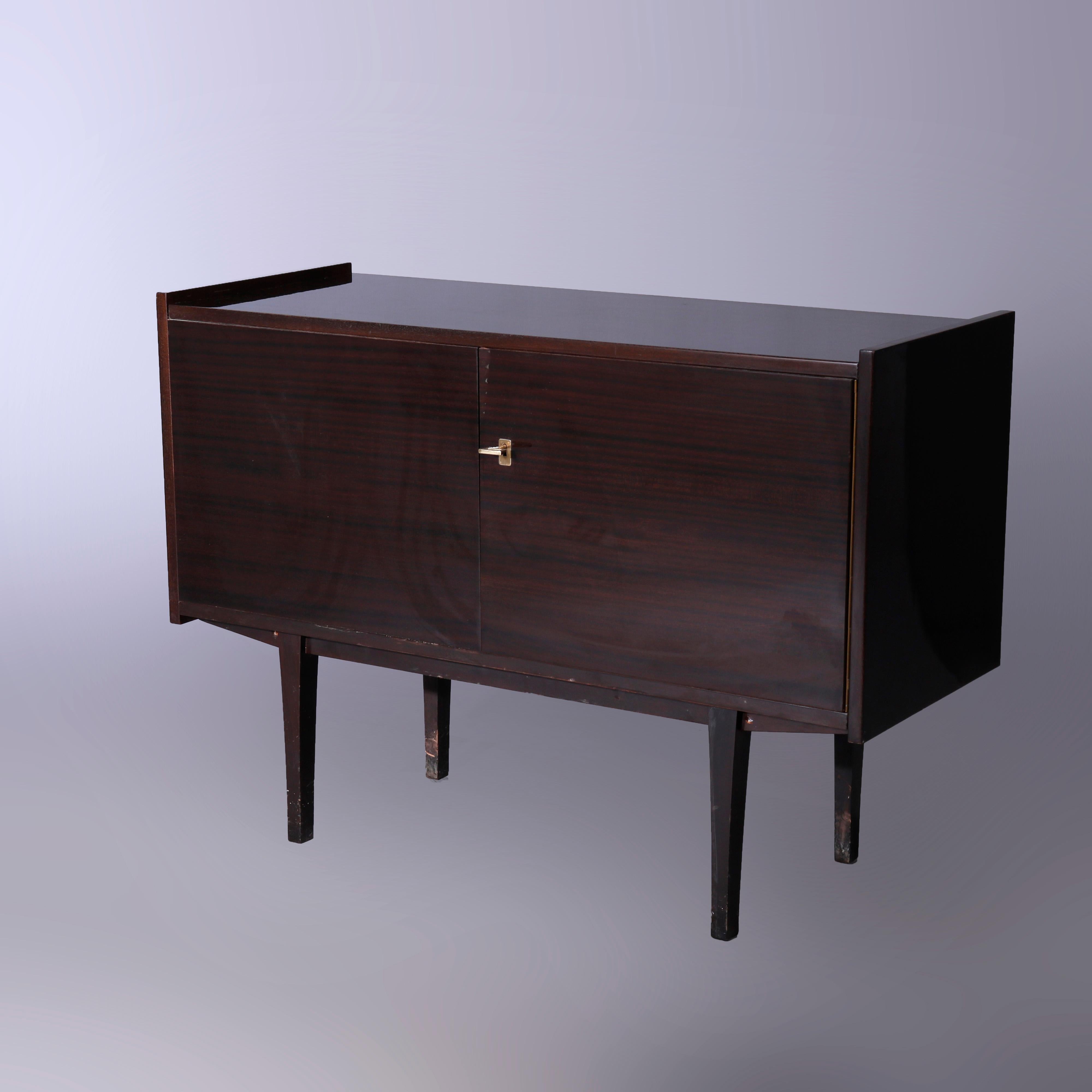A Mid Century Modern credenza offers ebonized finish with double doors opening to shelved interior, raised on square, straight and tapered legs, c1960

Measures - 29''H x 41''W x 16''D.

Catalogue Note: Ask about DISCOUNTED DELIVERY RATES available
