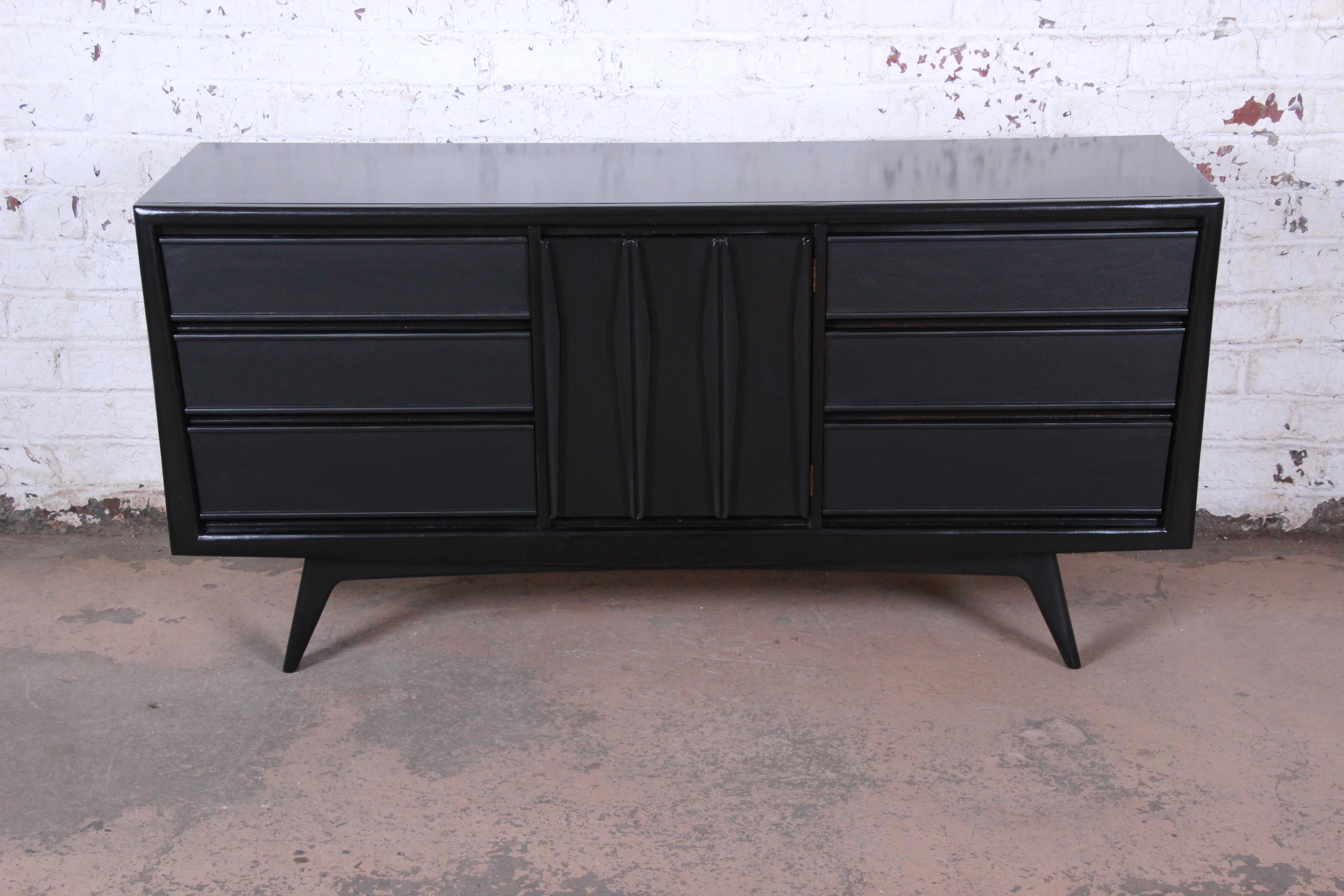 A gorgeous Mid-Century Modern sculpted walnut triple dresser or credenza by United Furniture. The dresser features beautiful walnut wood grain with a newly ebonized finish and sleek Mid-Century Modern design. It offers ample storage, with nine