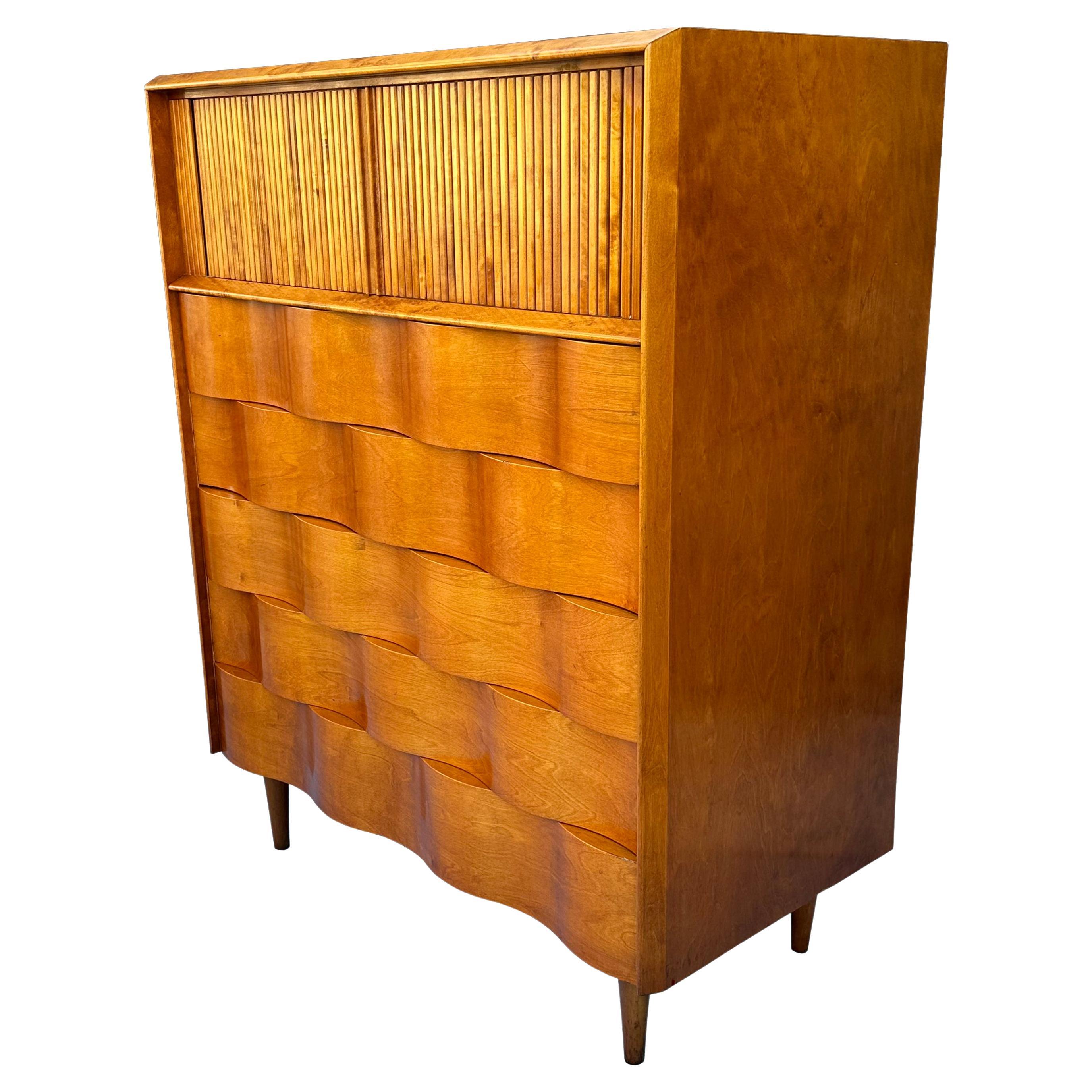 Mid Century Modern wavey front highboy gentleman's chest.  Gorgeous birch wood sculptural design featuring tambor door cabinet on top and 5 drawers below, atop 4 long dowel legs.  Designed by Edmond Spence and manufactured in Sweden. This would