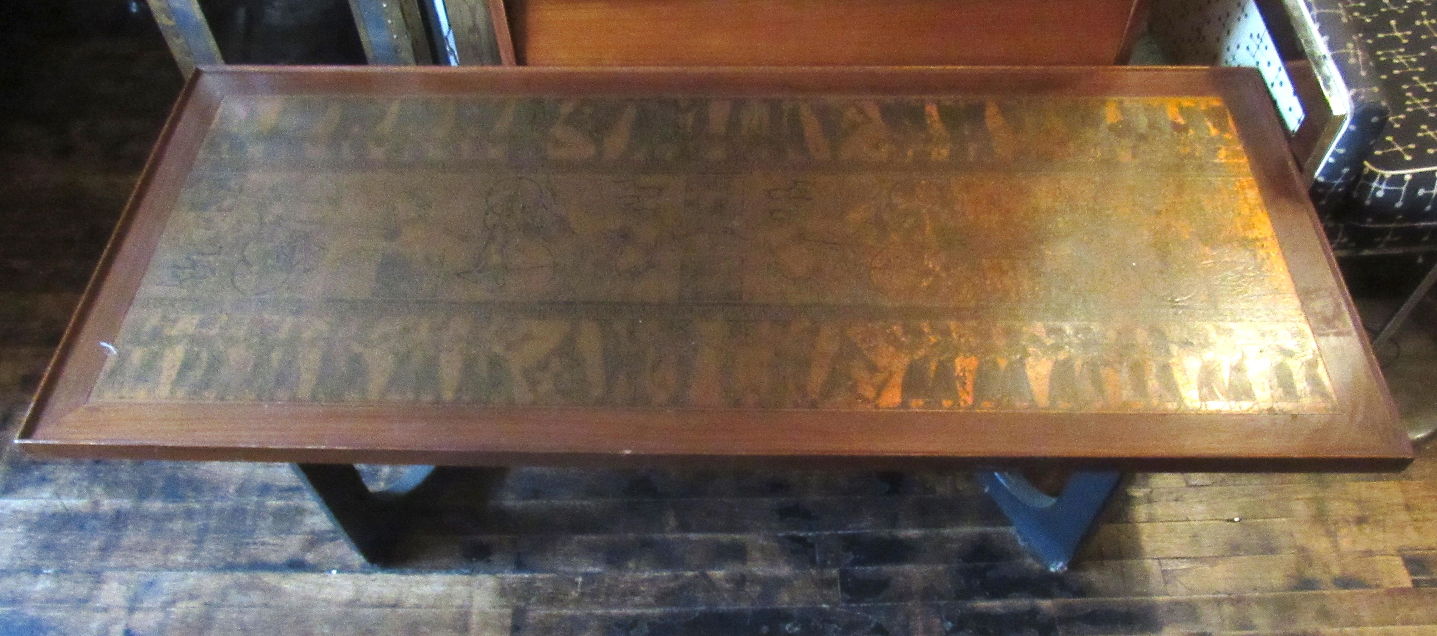 Beautiful unique vintage modern coffee table. This wood coffee table features a copper finished metal inlay embossed with beautiful Egyptian style hieroglyph artwork. The table sits on sculptural black wood legs. This stunning table would make a