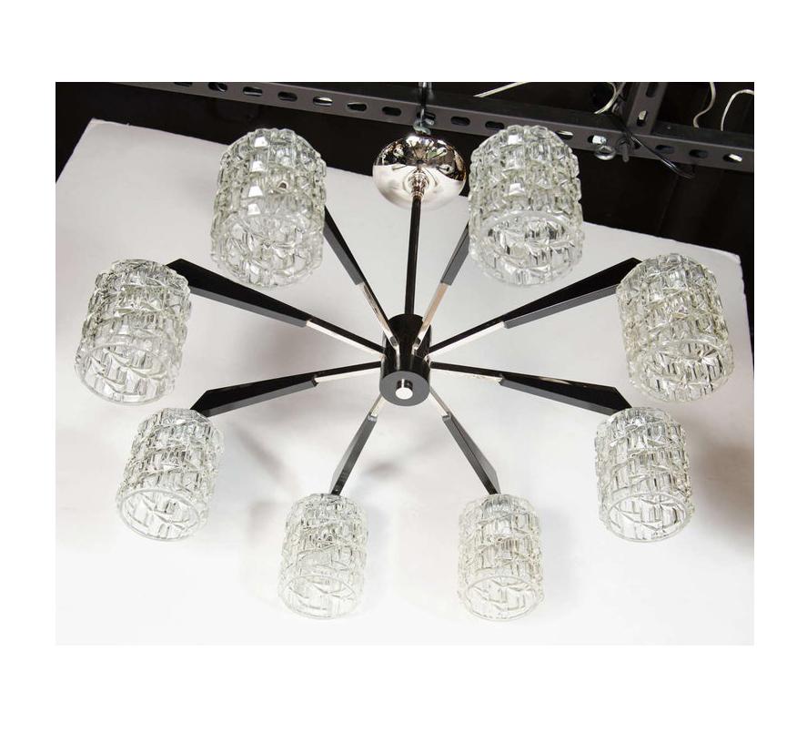 This graphic Mid-Century Modern chandelier was realized in Denmark, circa 1960. It offers eight-arms emanating from a cylindrical body in ebonized walnut with a chrome finial of the same shape adorning its base. The chrome arms have geometric
