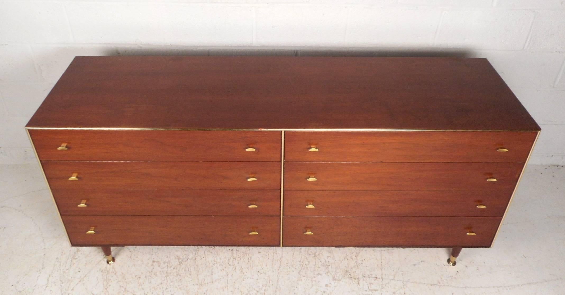 This stunning vintage modern dresser features eight large drawers with sculpted brass pulls on each. A unique design with brass trim running along the edges of the front and brass feet. Quality construction by R-Way with tapered legs and a beautiful