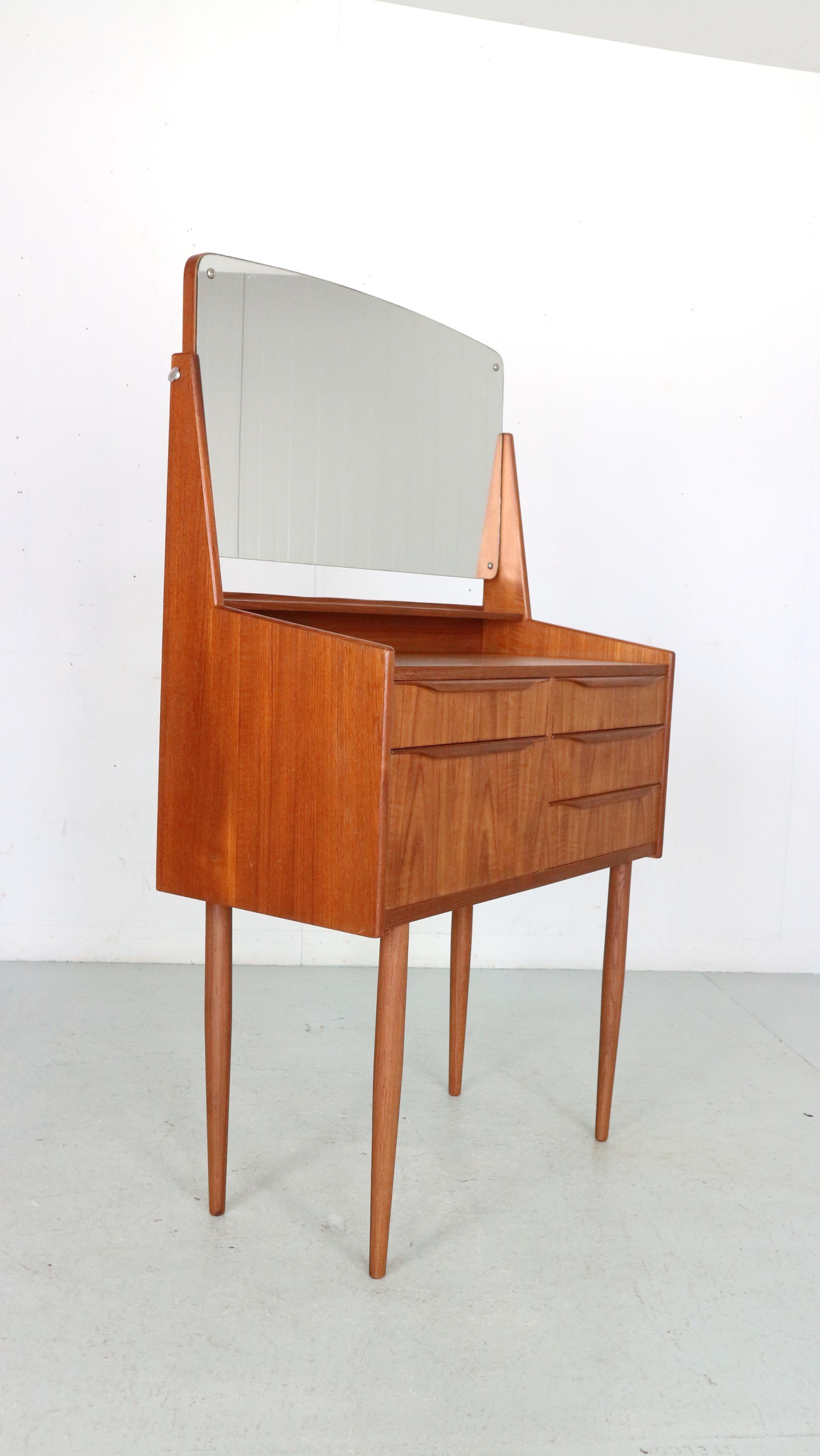 Mid-Century Modern period vanity or make up table made in Denmark, 1960. 
Teak veneer wood with solid teak handles and feet.
 Five drawers and adjustable mirror.
 In a good condition, beautiful and elegant piece. 

The mirror and the legs can
