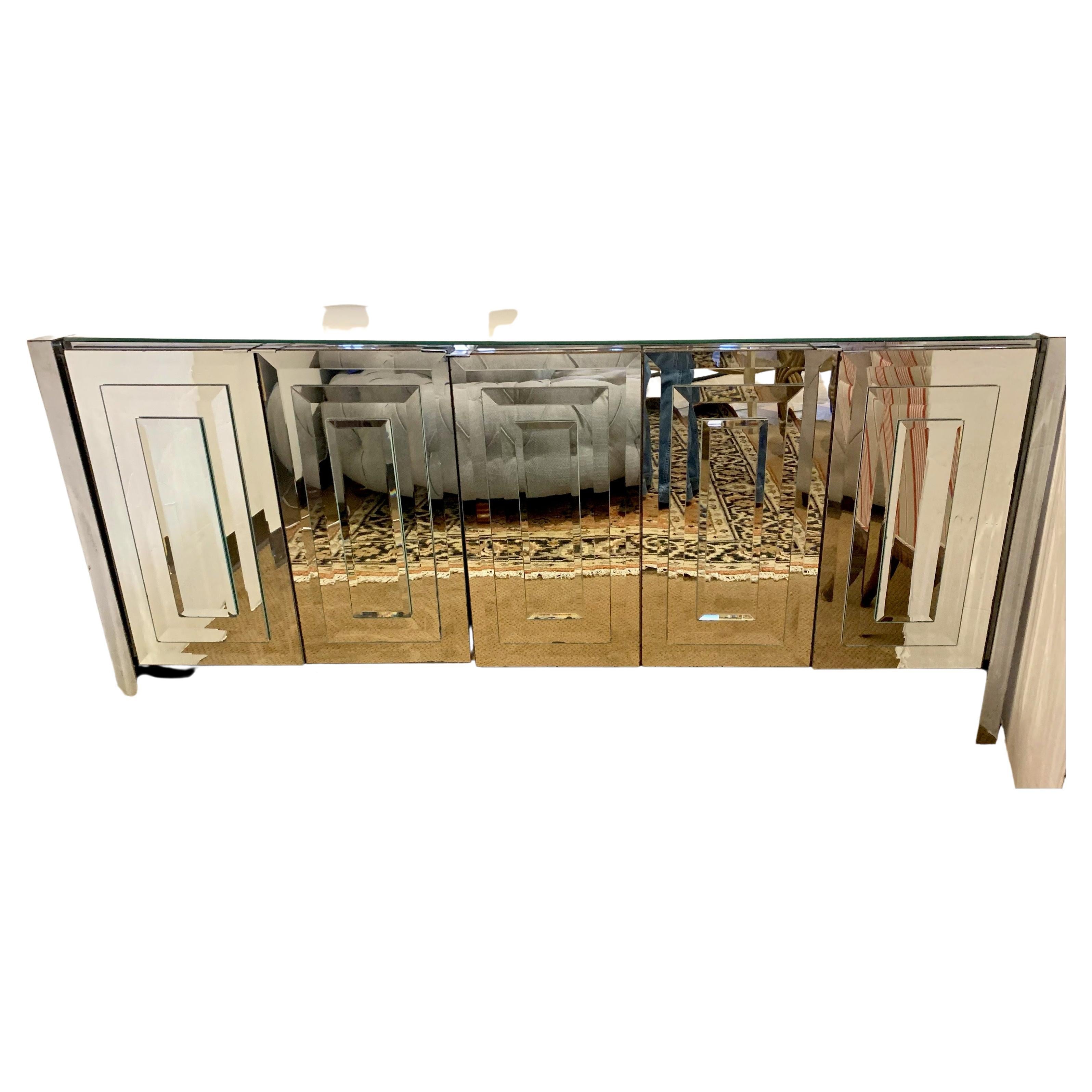 Glamorous mirrored credenza cabinet circa 1970s. Each of the five doors is mirrored in beveled and layered mirror in graduating sizes, the top and sides are also mirrored. The left three side doors open to white laminate drawers. The two right doors