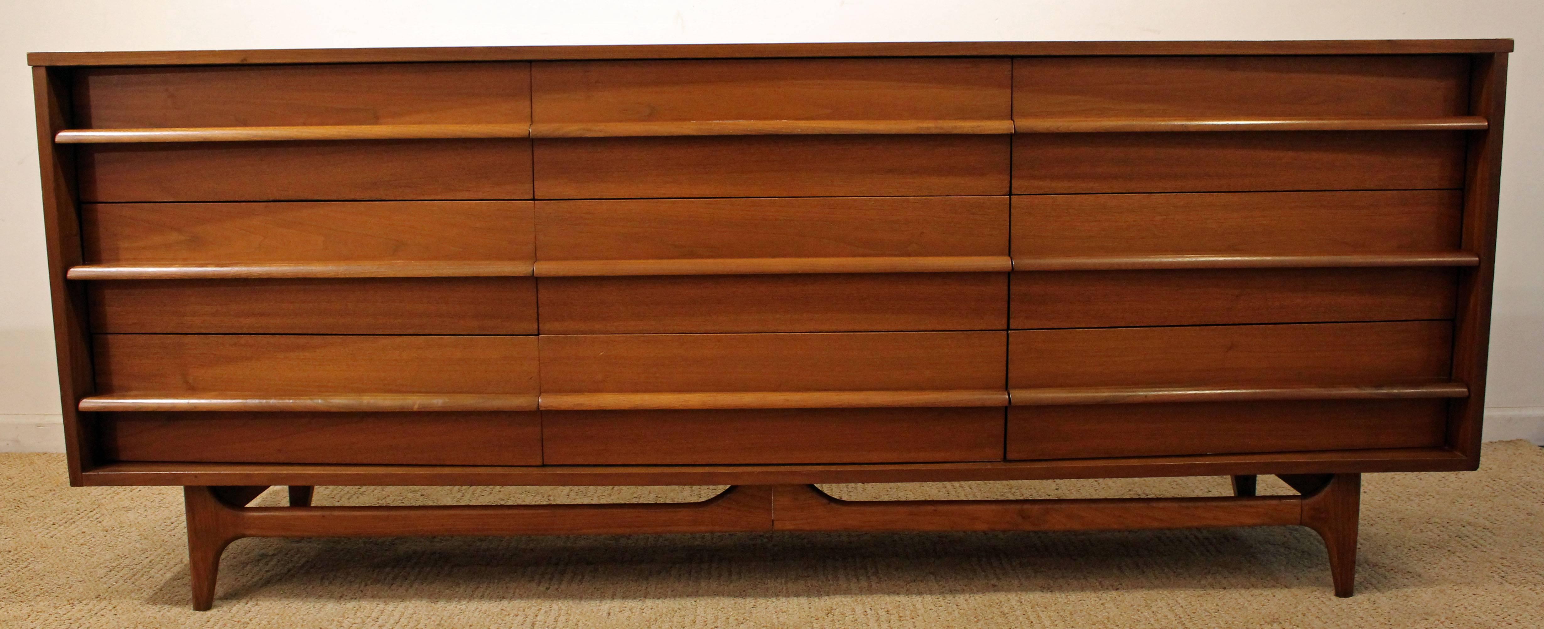 This piece is made of walnut, featuring a curved front and nine dovetailed drawers with sculpted pulls. In excellent condition, has been refinished. It is marked by YMC (Young Manufacturing Co). 

Dimensions: 
80
