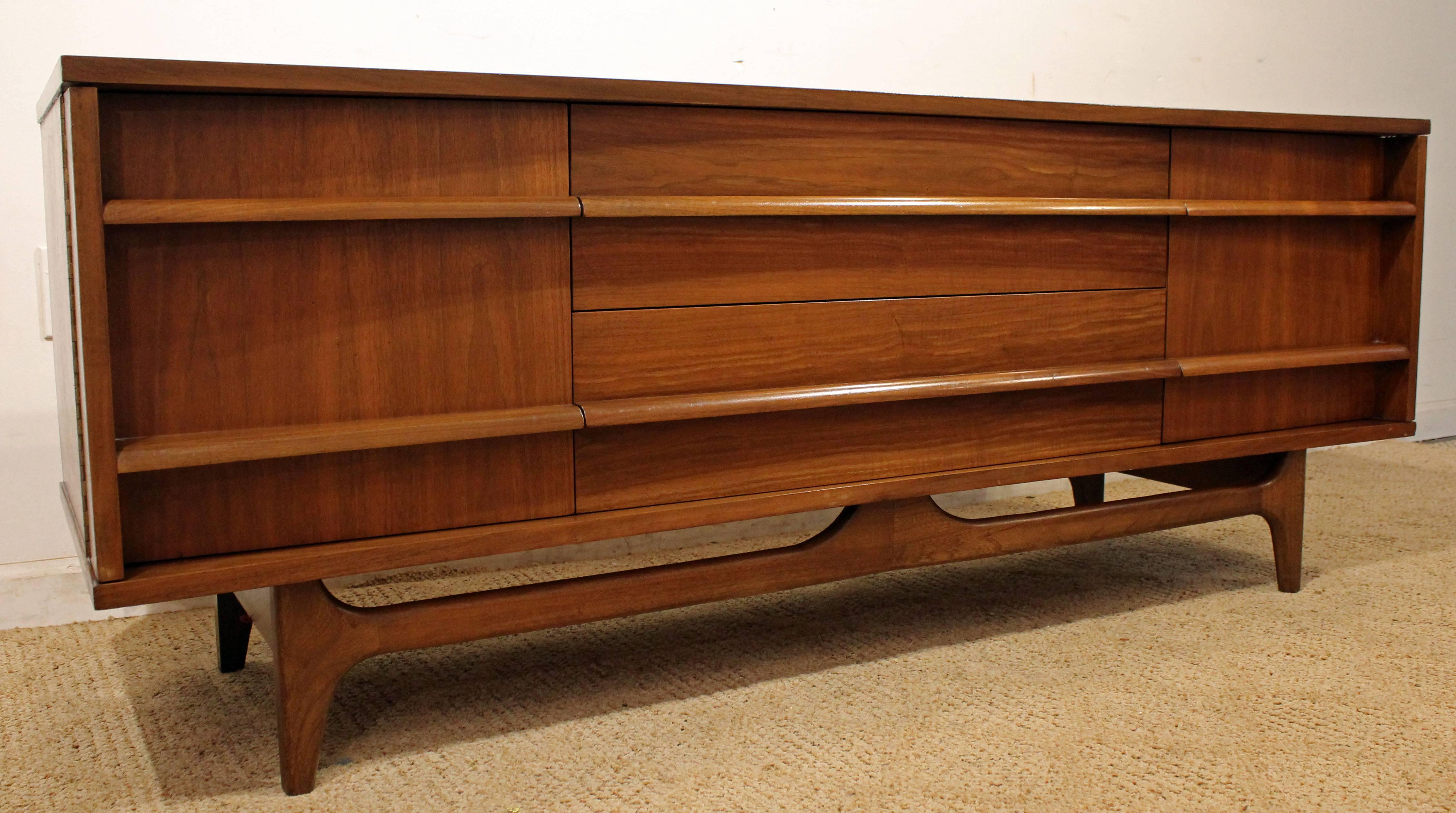 This piece is made of walnut, featuring a curved front, two doors on either side and three center drawers with sculpted pulls. It has been refinished.

Dimensions: 
64