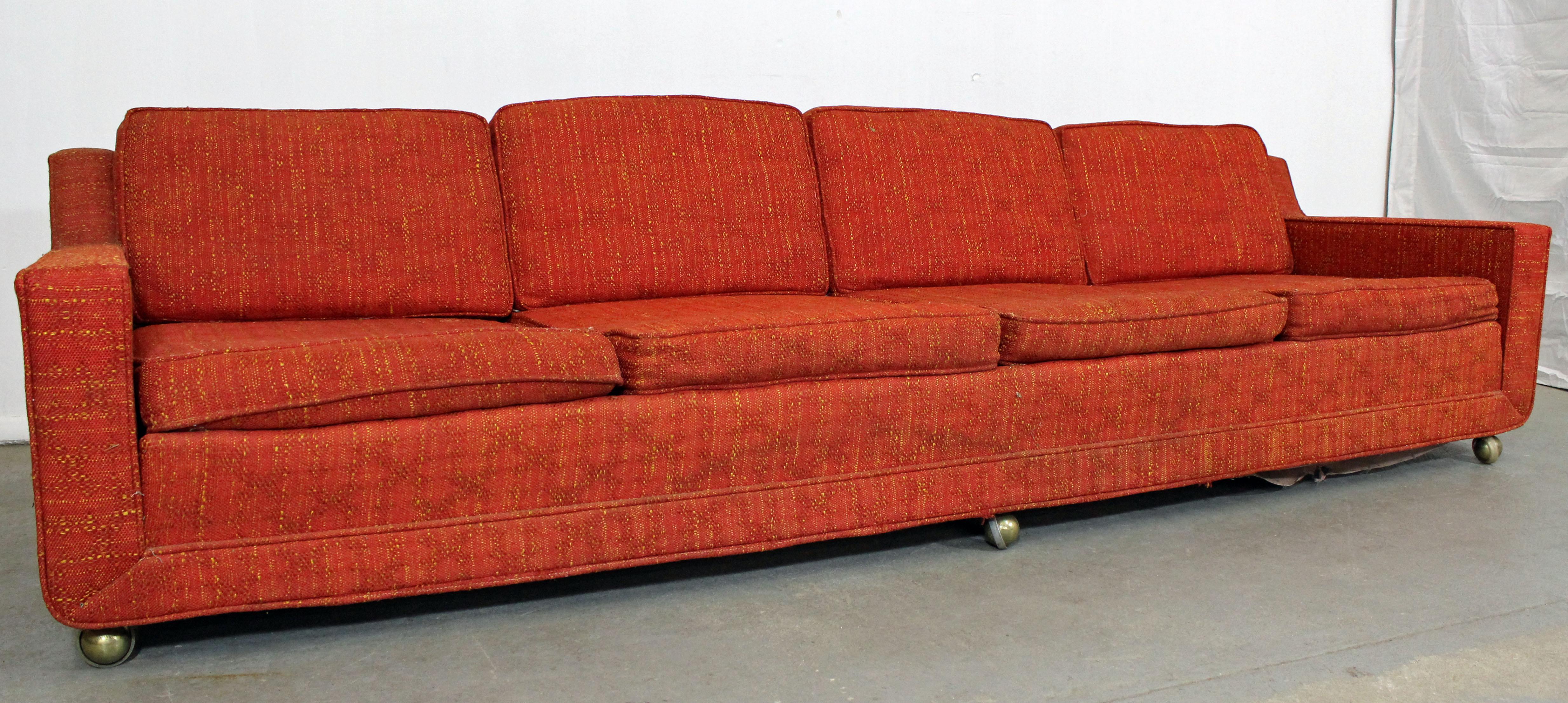 What a find. Offered is an elongated midcentury sofa with four seats by Kroehler. Features three caster wheels in front and wood legs in back, which makes for easy moving. Perfect for entertaining! It is structurally sound showing age wear. Will