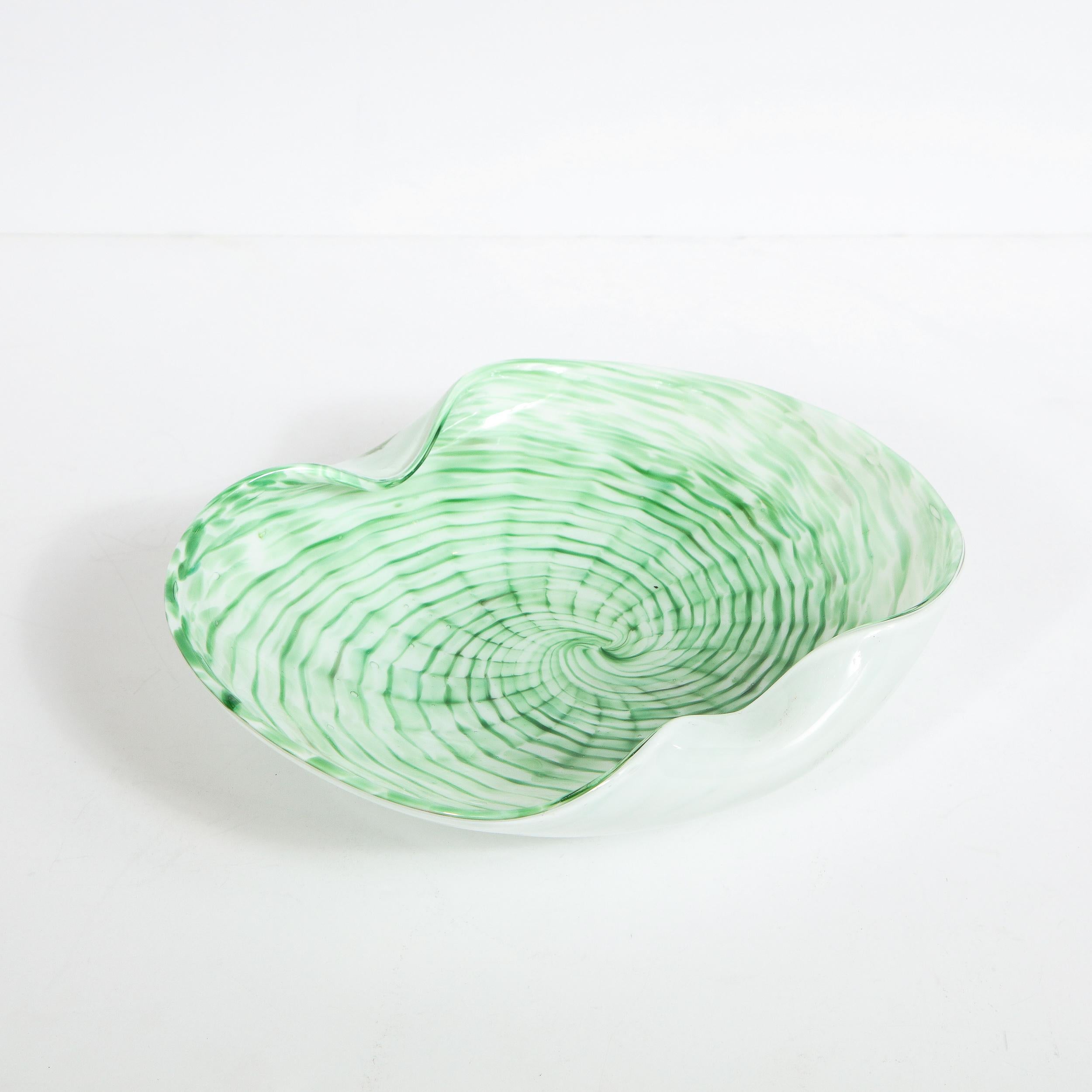 This elegant Mid-Century Modern decorative bowl was hand blown in Murano, Italy- the island off the coast of Venice renowned for centuries for its superlative glass production. It offers a circular form with two indented ends. Its outside is