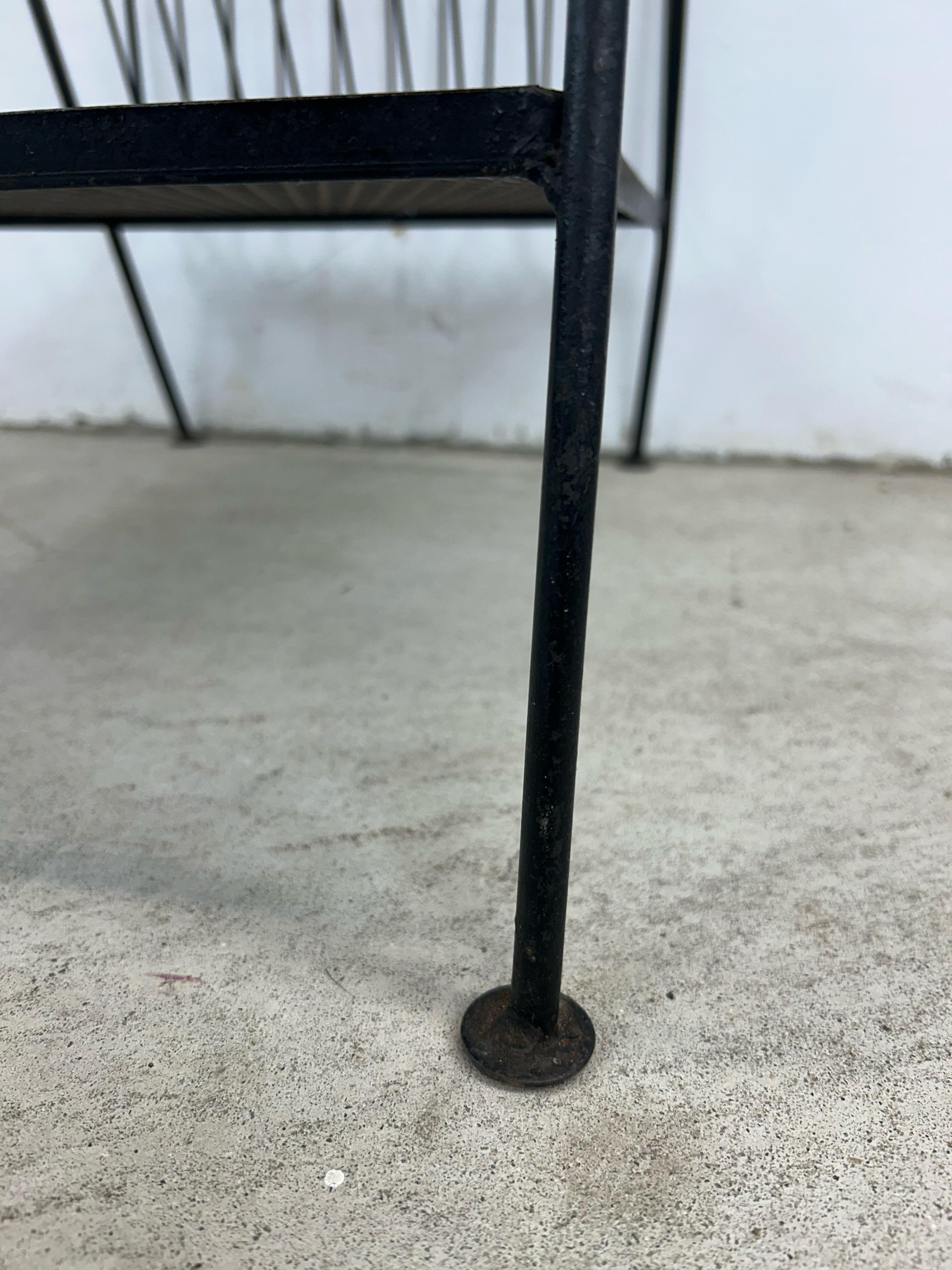 This mid century modern end table features durable Formica top with faux wood grain finish and black painted metal frame with built in magazine rack. 
 Dimensions: 23.5w 16.5d 21.5h 20sh 28.5ah

Condition:  Formica top has some edge dings and deep