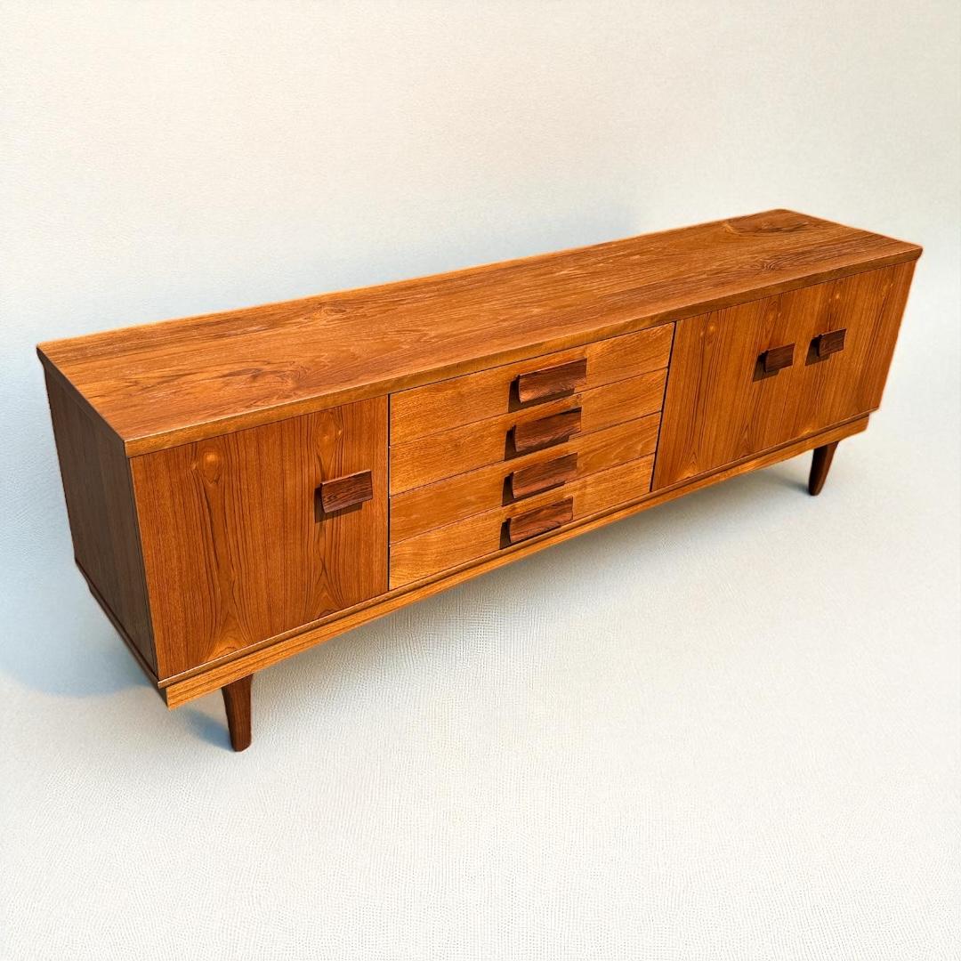 Vollständig neu lackierte Vintage 1960's Mid Century Modern lange Afromosia (African Teak) Credenza mit geschnitzten Rosenholz zieht zugeschrieben Bath Cabinet Makers England. Vollständig neu lackiert bietet diese große Kredenz reichlich Stauraum