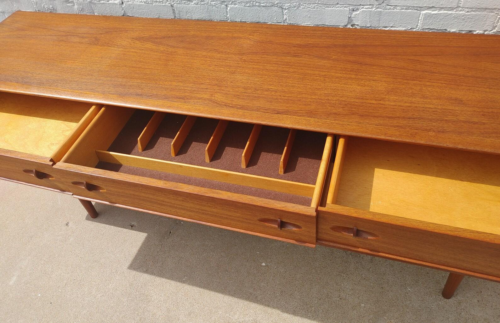 Credenza in teak moderna inglese del metà secolo
 
Condizioni vintage superiori alla media e strutturalmente solide. Presenta alcuni lievi segni di usura e graffi dovuti alla finitura. Il top è stato rifinito e non ha la finitura originale di