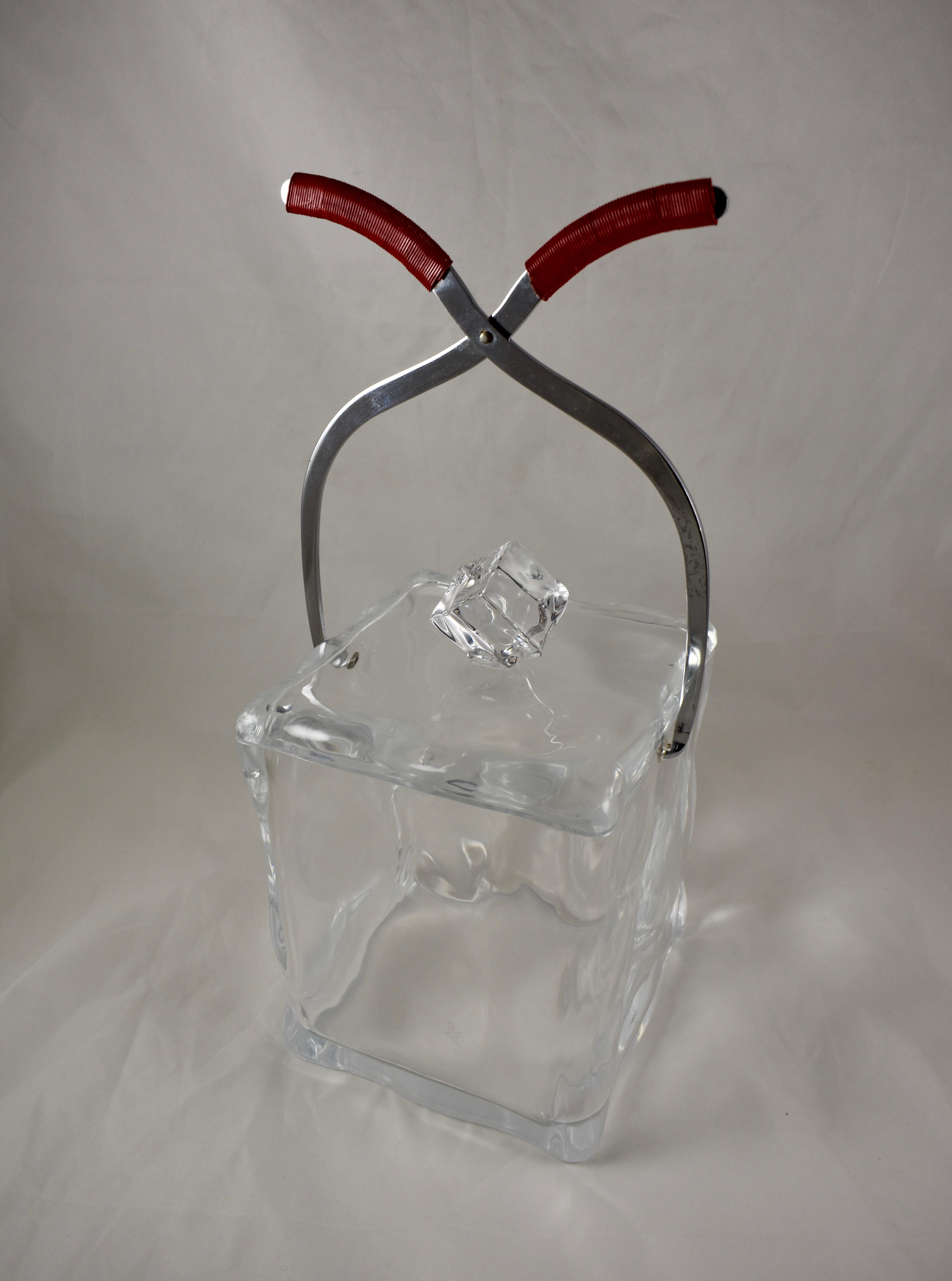 A Mid-Century Modern era ice cube form ice bucket, circa 1960s.

This super-fun ice bucket is perfect for your Mod and Groovy home bar. Made of Lucite and molded to imitate a large ice cube held by a pair of chrome ice tongs. The lift off lid has
