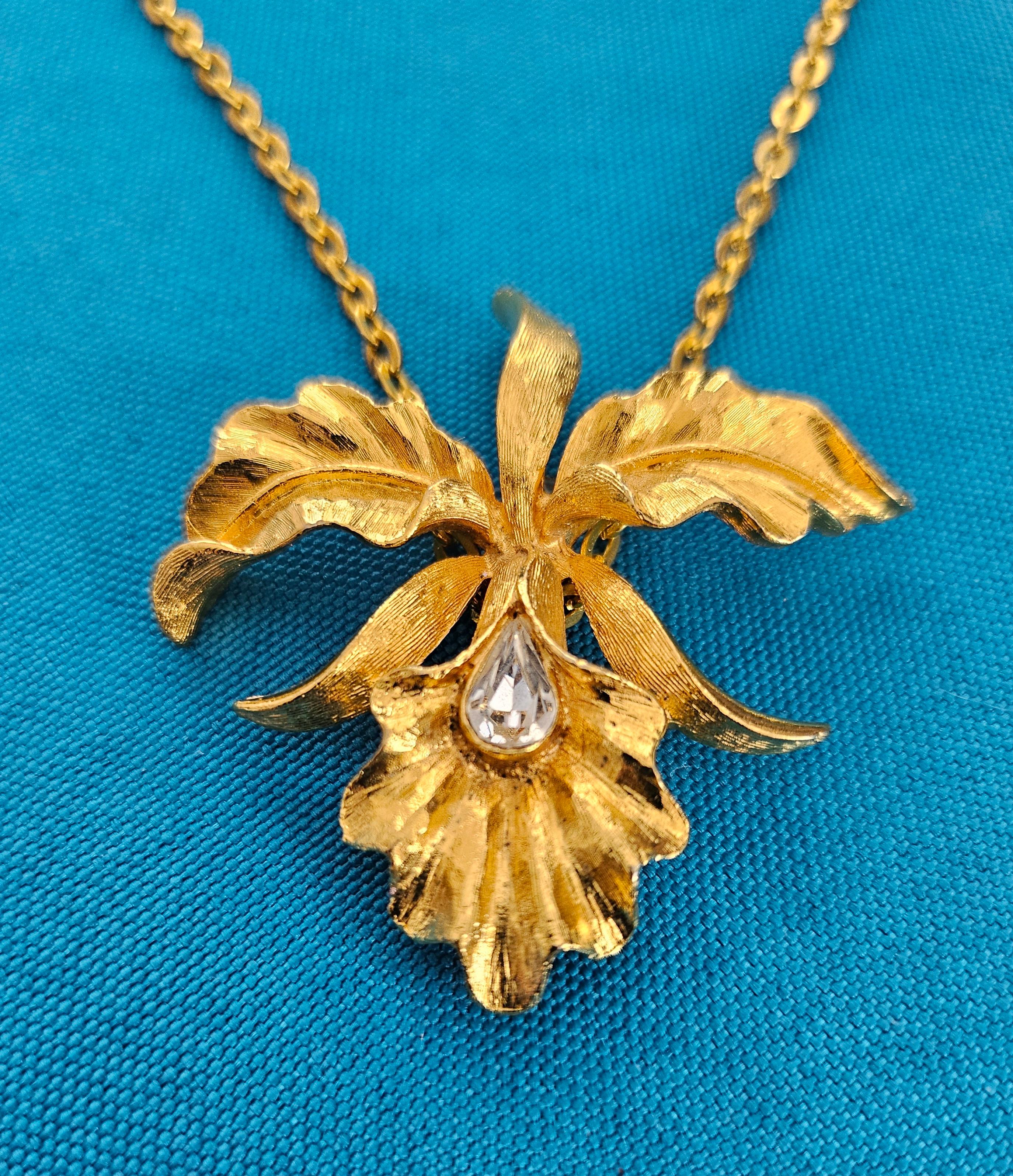 Collana con ciondolo a forma di orchidea in stile Mid-Century Modern Era.
Al centro c'è un cristallo sfaccettato, probabilmente Swarovski (?) dato che il pezzo reca il timbro Mamselle, che era noto per l'utilizzo di cristalli Swarovski.
Il retro