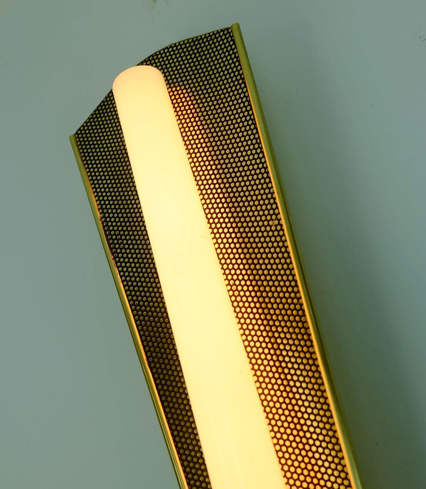 Elegant wall lamp by Erco from the 50s/60s. Made of gold-colored and black metal. With fluorescent tube (the tube is part of the offer). Drawbar switch. 

Dimensions in cm:
Length 37.5 cm, max. width 13 cm, depth 6 cm.

Dimensions in inches: 
Length