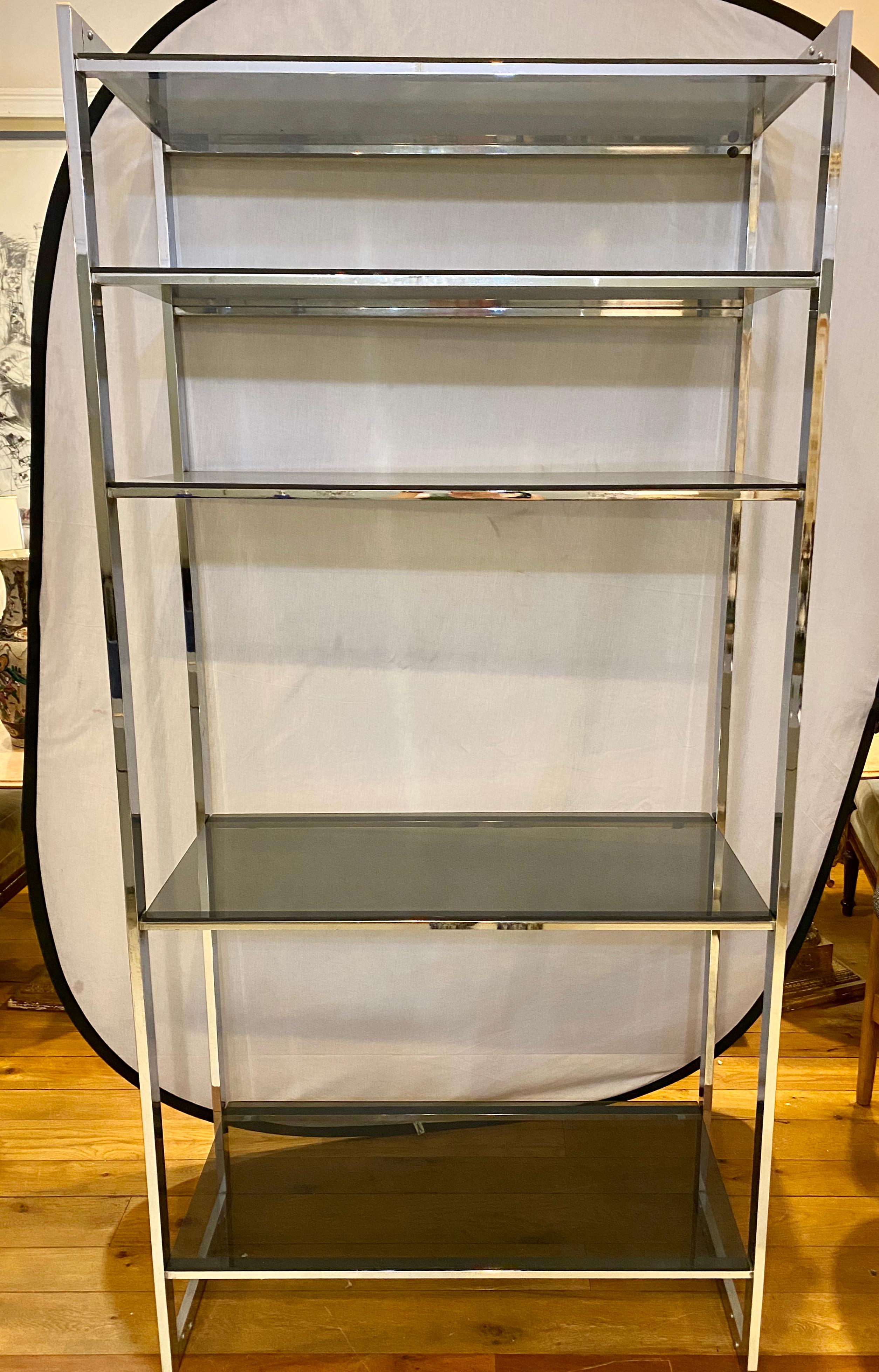 Mid-Century Modern étagère chrome base smoke glass shelves. This sleek and stylish shelving unit is simply stunning and is certain to make a fine addition to any space in the home.