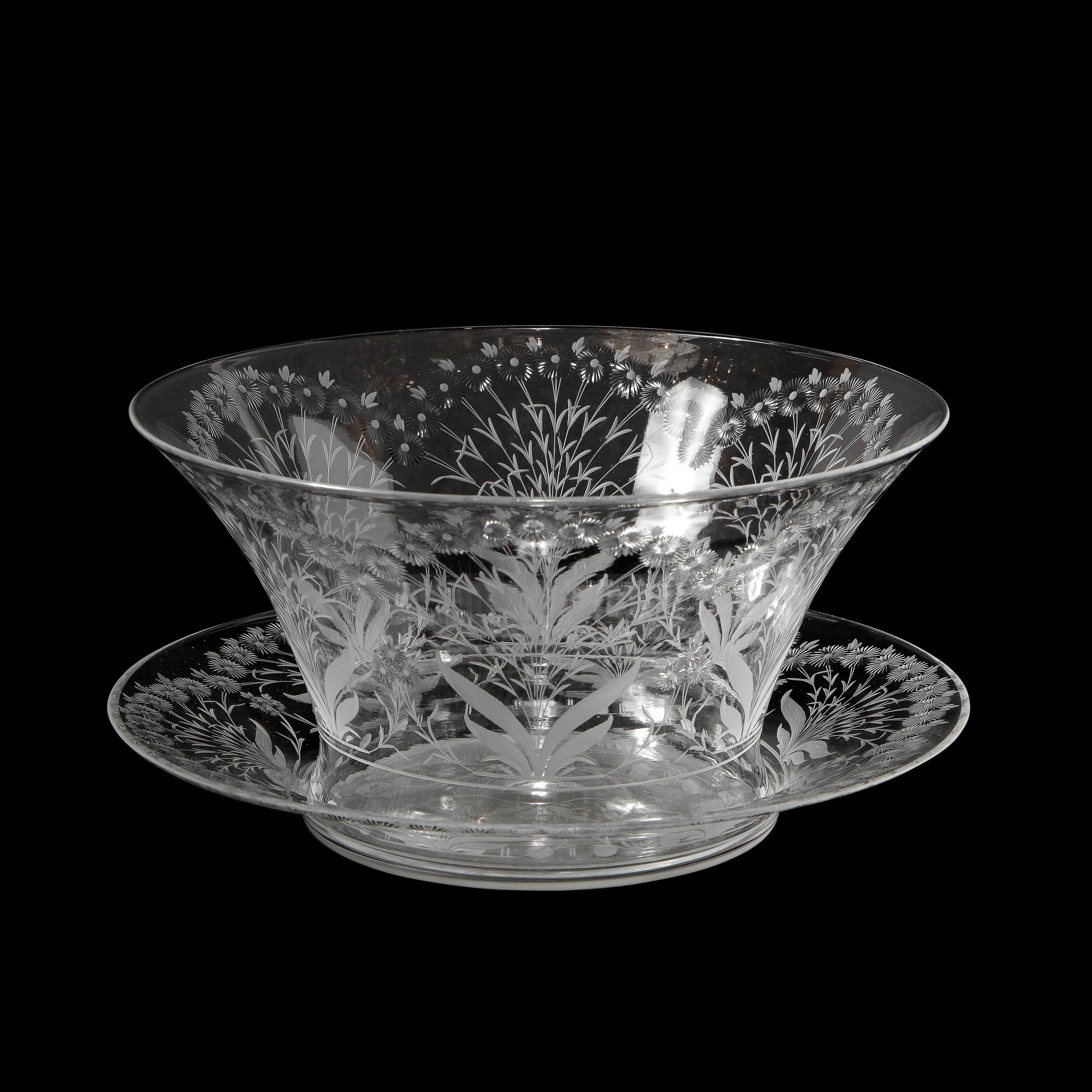 This beautiful Mid-Century Modern bowl with serving dish was realized by the esteemed maker Kosta Boda in Sweden, circa 1960. It features a conical form with a flared circular mouth in translucent glass with frosted foliate designs and etched