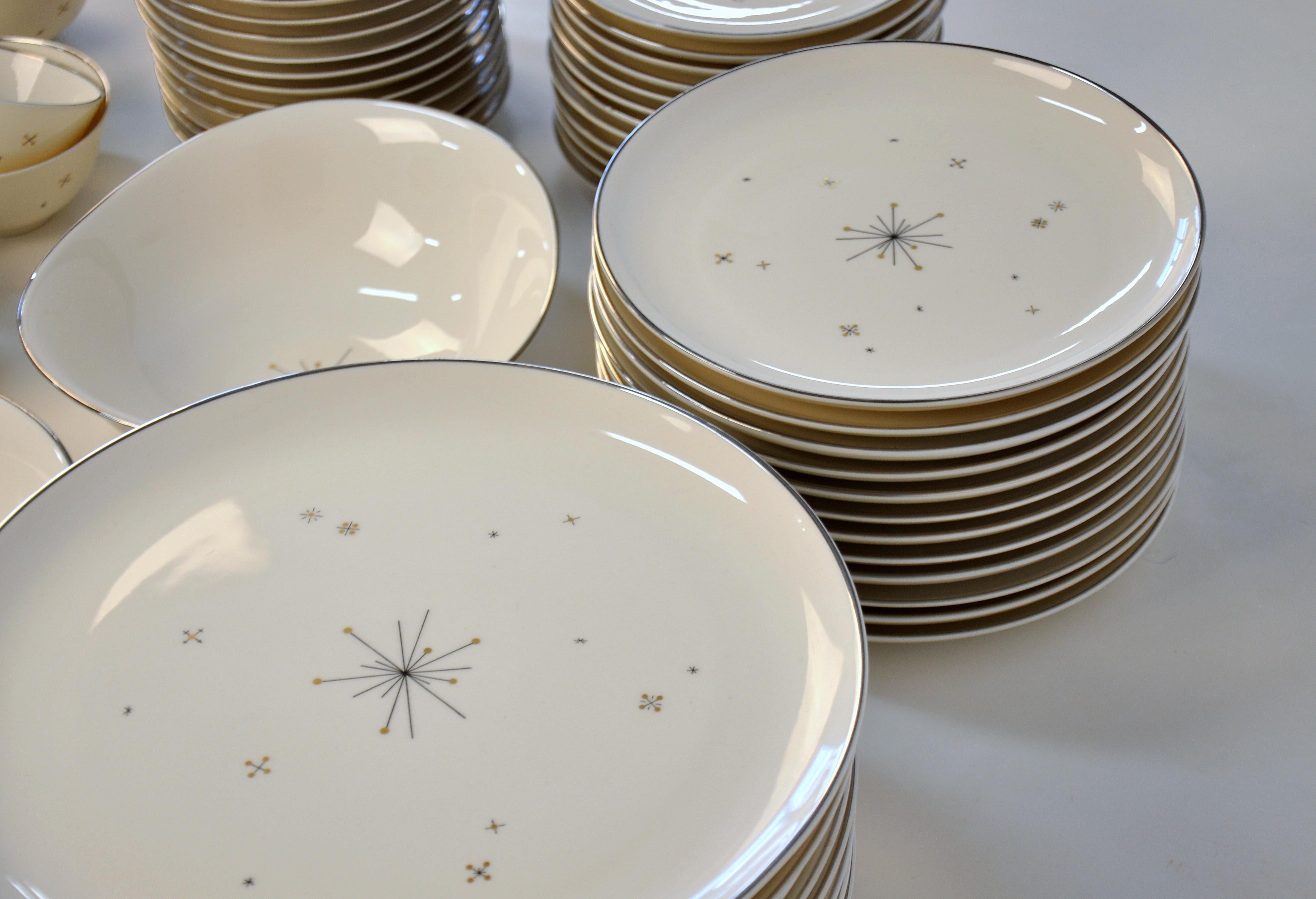 Fabulous midcentury atomic 12 person dinnerware dish set in the Evening Star pattern by Syracuse China, dating from the late 1950s-early 1960s. Featuring black and gold stars on an ivory / cream / off-white background, with silver / platinum rims.
