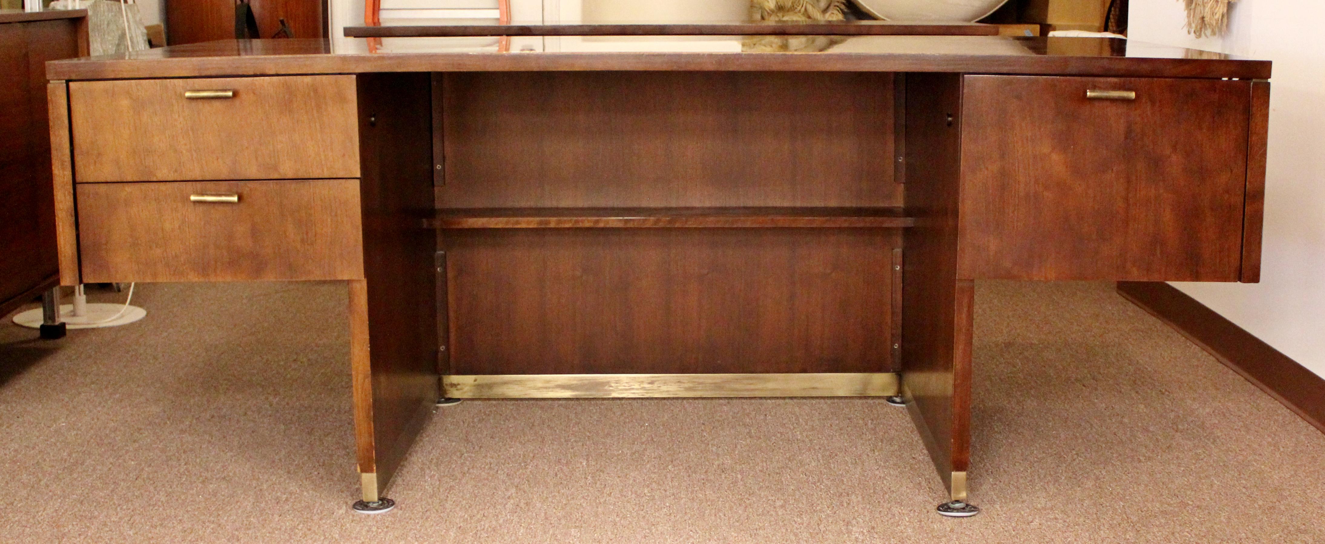 For your consideration is an incredible, executive cantilever desk and cabinet credenza set, made by Myrtle Desk, both with brass accents, circa 1960s. Walnut body of the desk is an open pedestal base with recessed shelf and brass inlay. The drawers