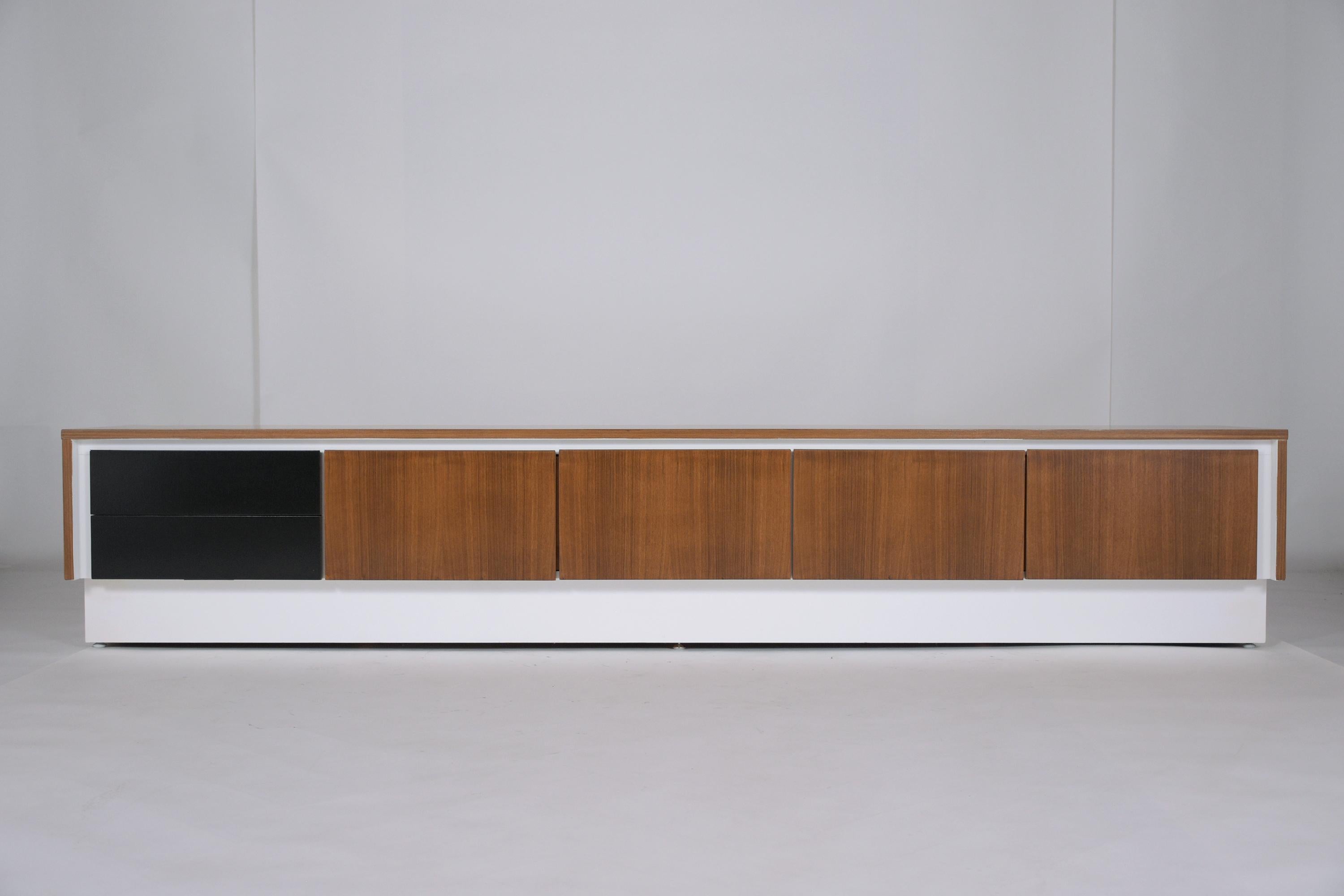 An extraordinary 1960s mid-century executive credenza beautifully hand-crafted and has been newly restored and refinished by our team of craftsmen. This long cabinet features a sleek walnut, black and white combination color in a lacquered finished,