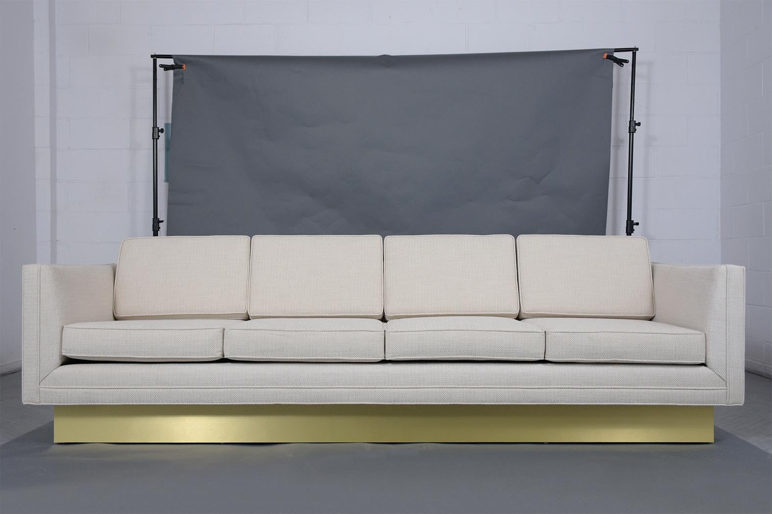 Dive into the essence of mid-century modern perfection with our beautifully restored vintage executive sofa. Constructed from solid wood and reupholstered in an elegant off-white fabric, this tuxedo-style sofa exudes timeless appeal and luxury,