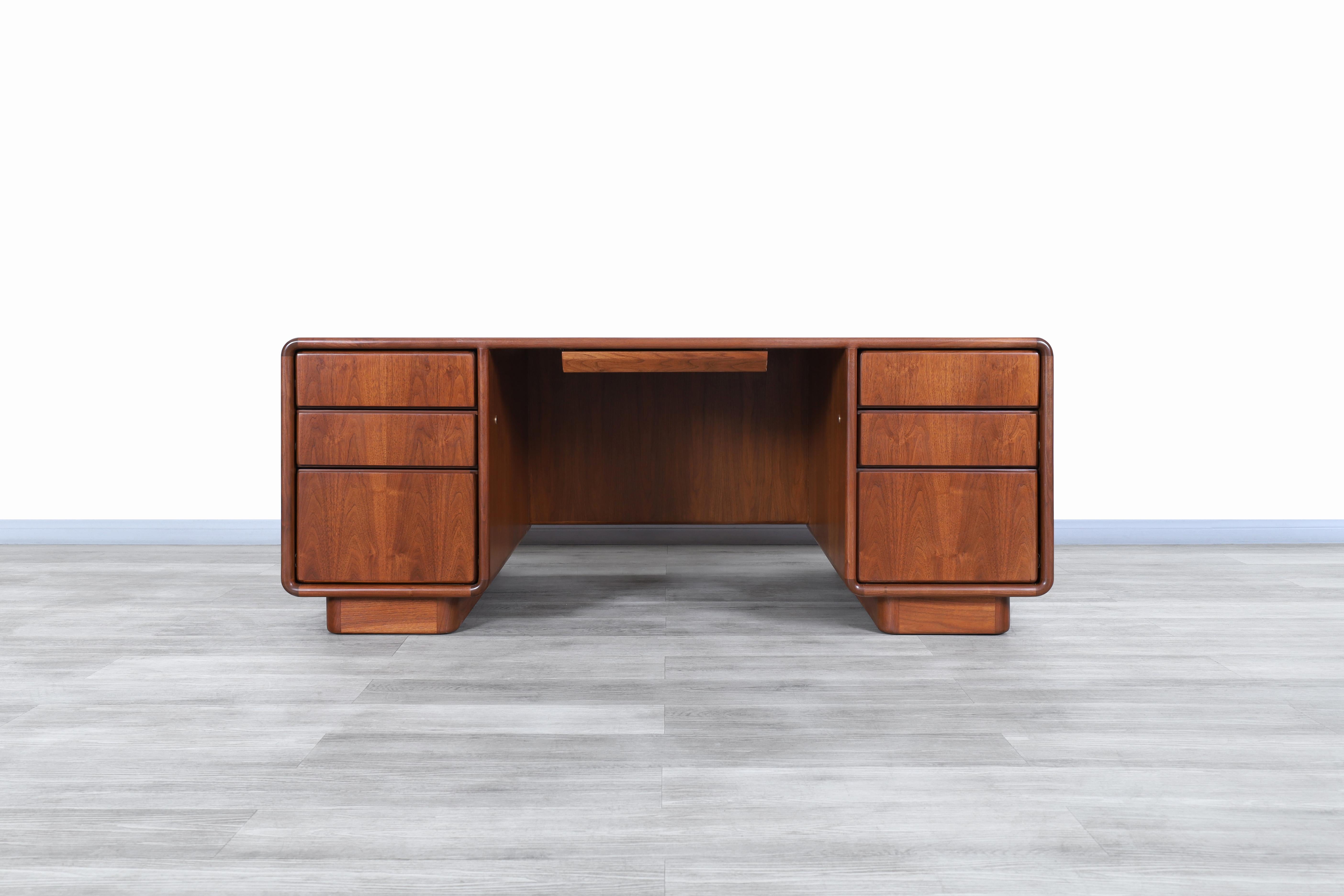 Exceptional Mid-Century Modern executive walnut desk manufactured and designed in the United States, circa 1950s. This desk has been built from the highest quality walnut wood and has a Minimalist but highly functional design where the construction