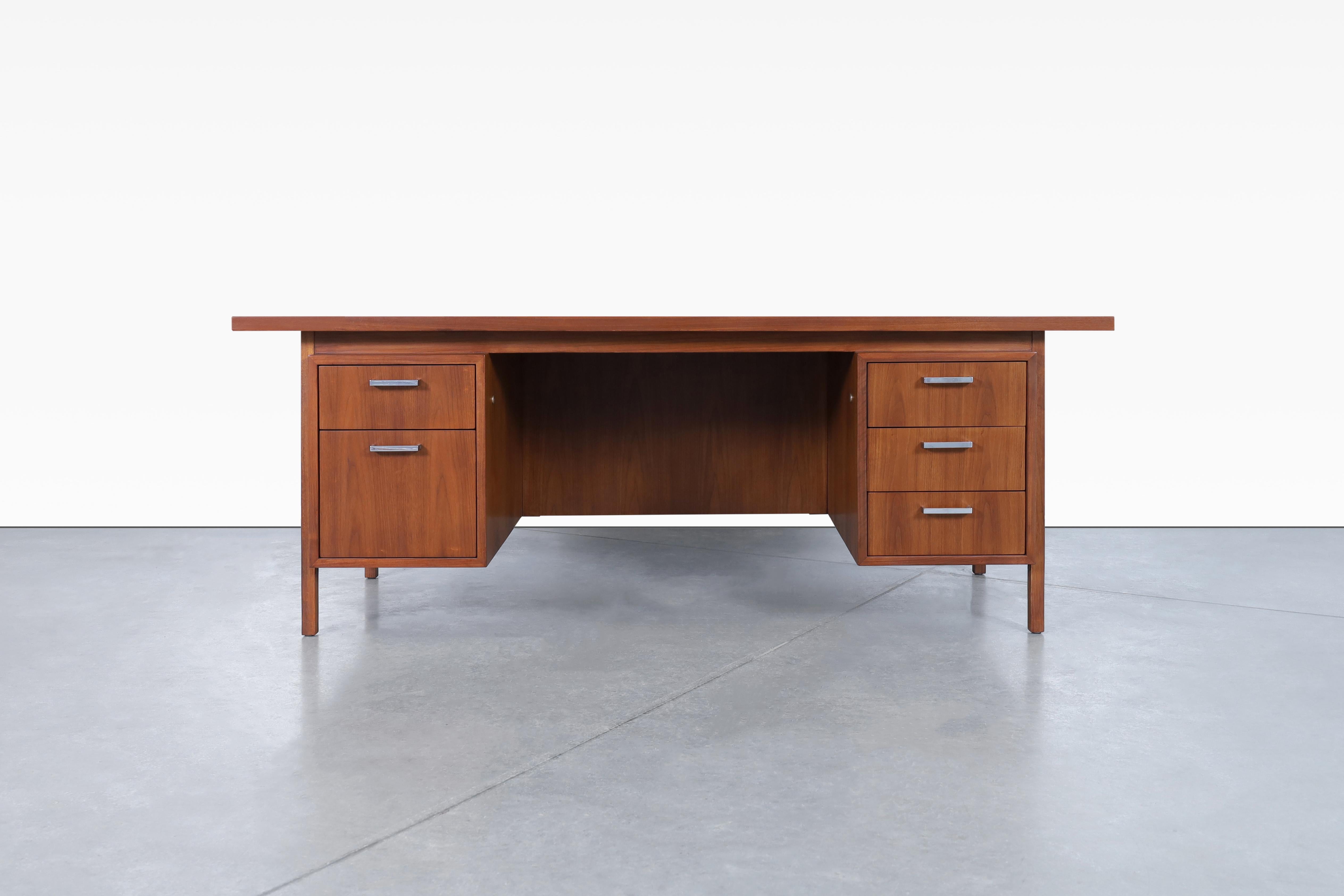 Stunning mid-century modern walnut executive desk made in the USA, circa 1960's. This desk features a well-crafted walnut design accented by elegant chrome handles. Designed with functionality in mind, it has four drawers and a spacious file drawer,