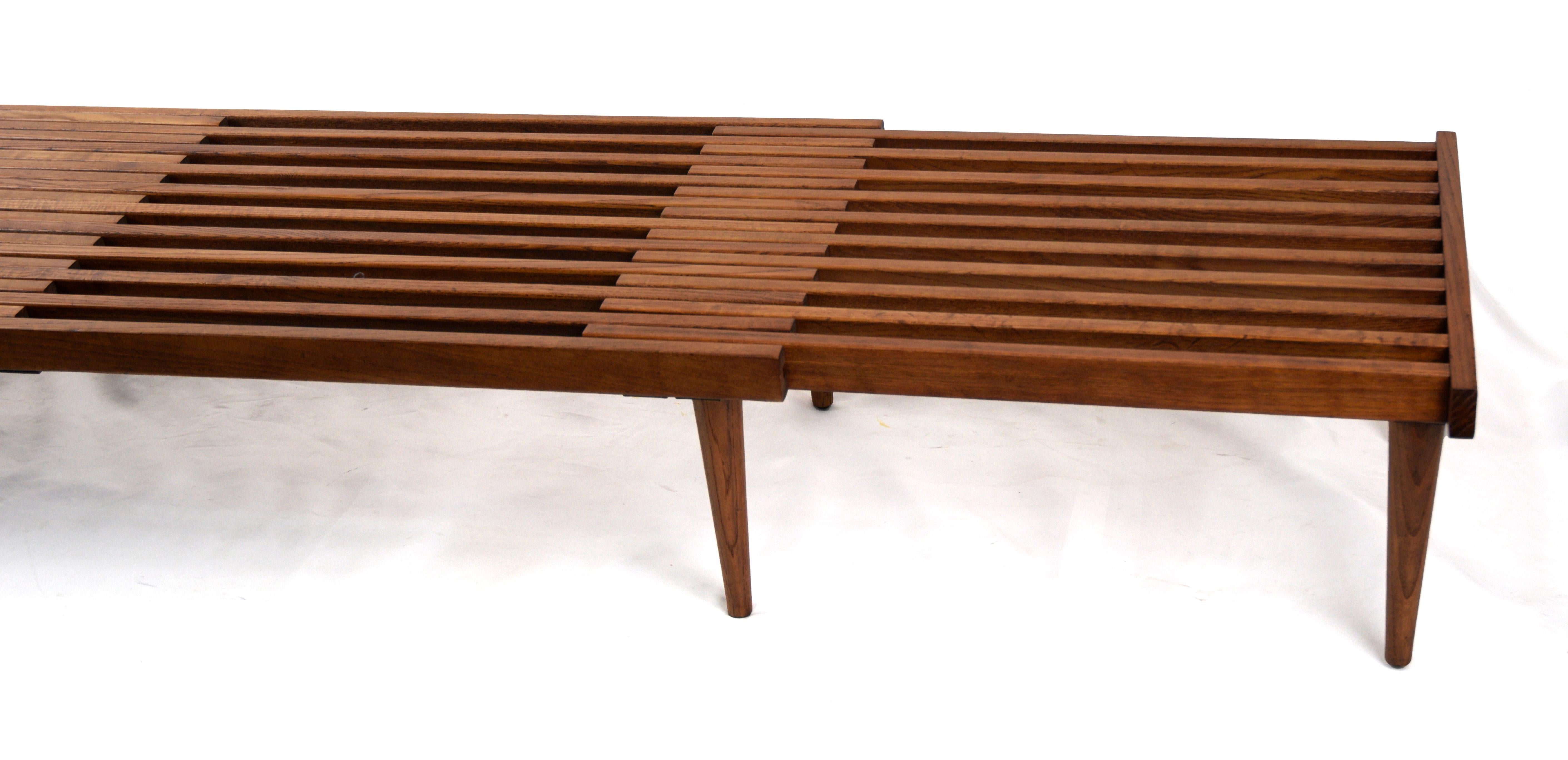 Beautiful and versatile expandable mid century minimalist walnut slat bench designed by John Keal for Brown Saltman, circa 1960. This California modern piece features an expandable sliding top with eight support legs. Perfect to use as a living room