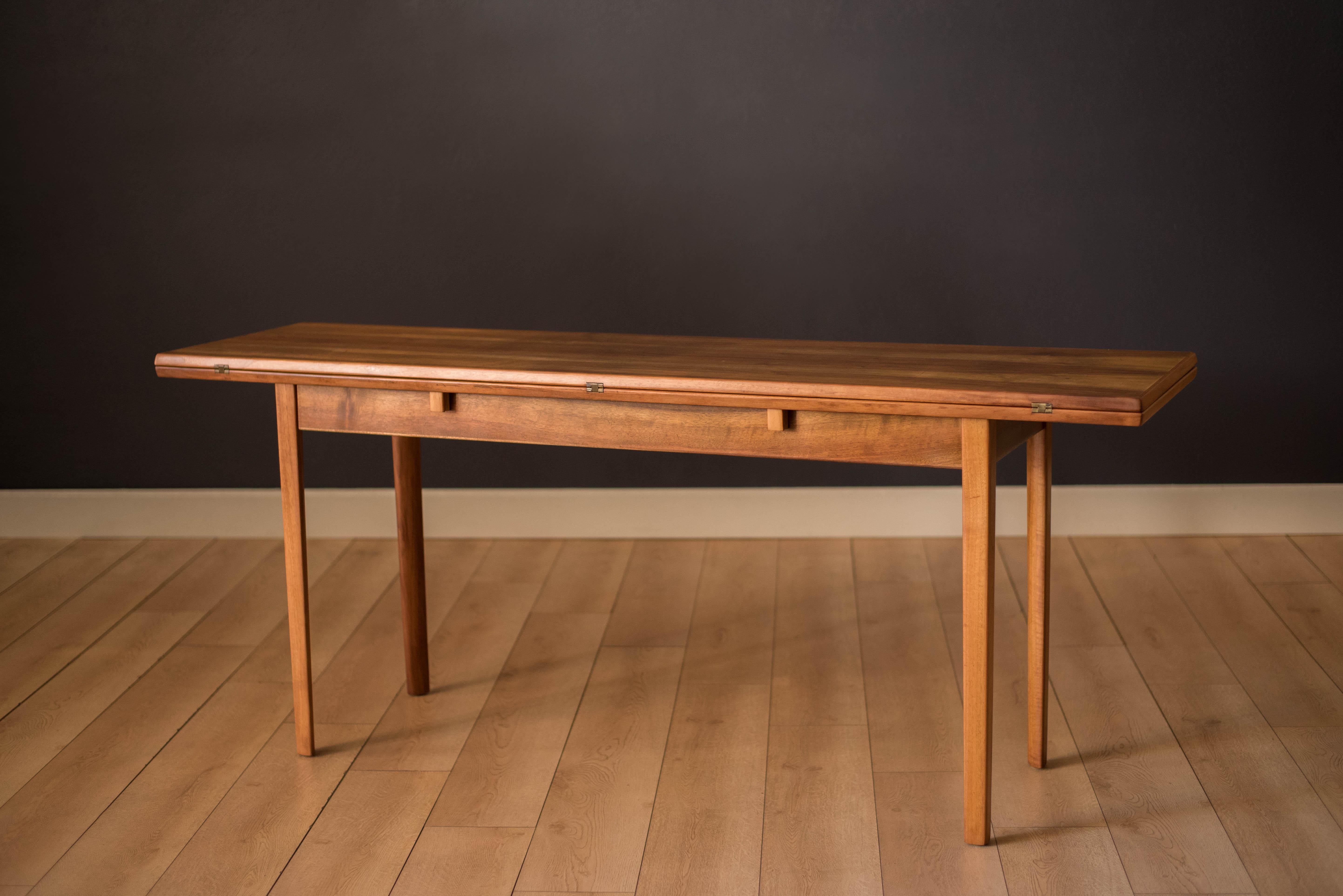 Vintage Scandinavian extending console table in walnut circa 1960's. This clever design features an expanding flip top that slides over converting the console into a dining table. Equipped with brass hinges and curved tapered legs, this versatile