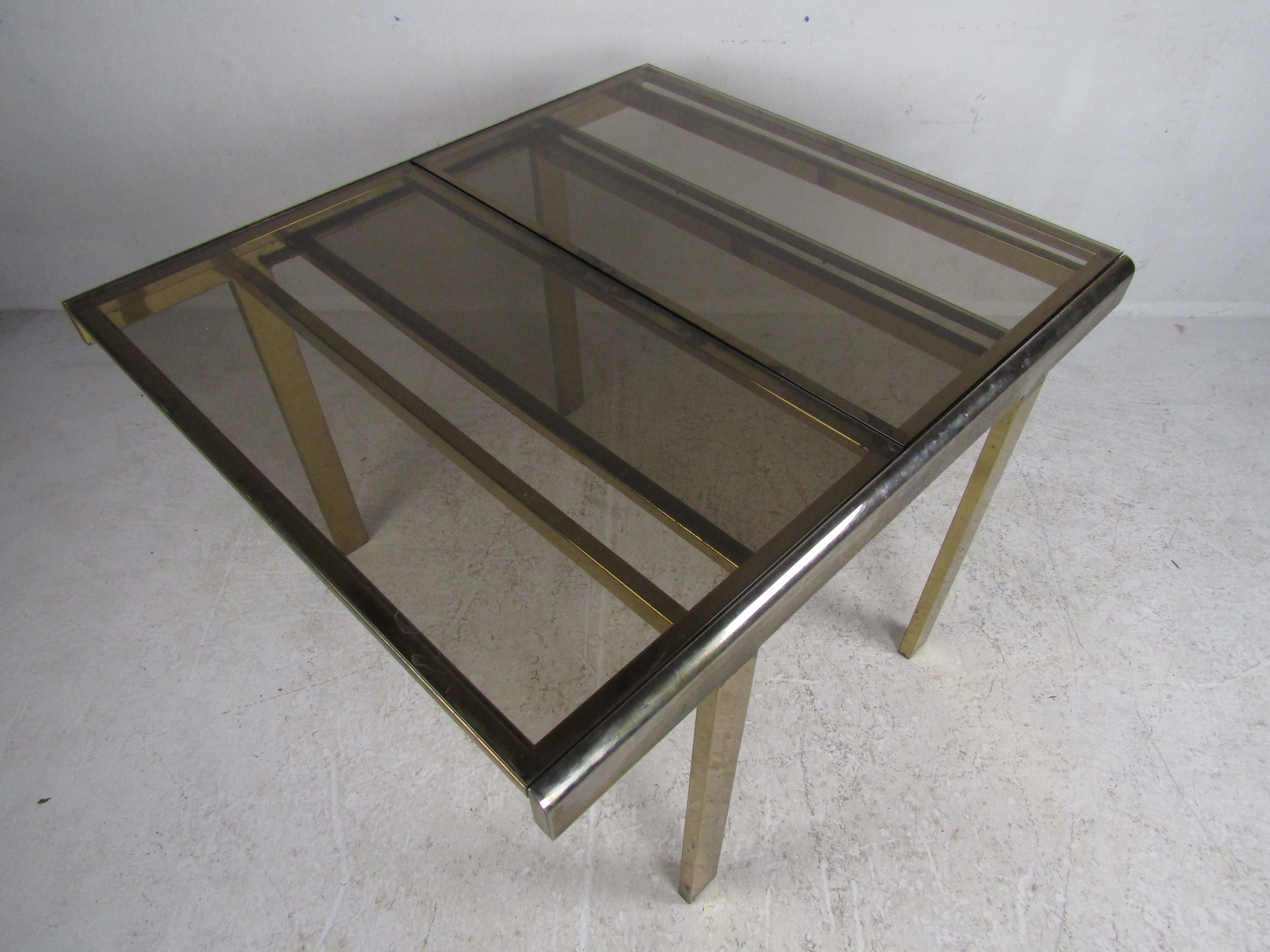 This vintage eye-catching Mastercraft style brass adjustable table with beautiful smoked/tinted glass conveniently expands to accommodate guests. Easily slides open to the length of 66