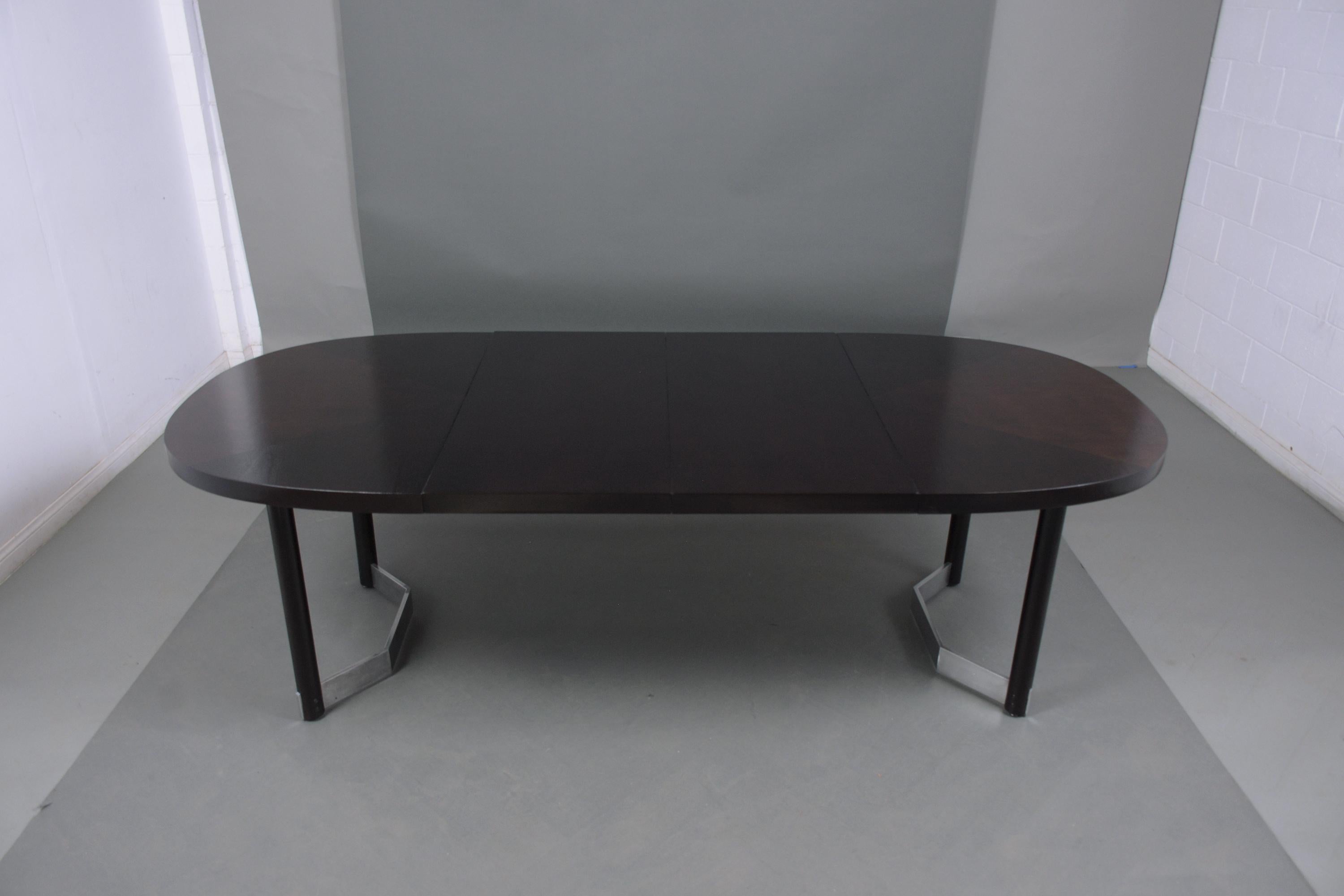 An extraordinary modern dining room table crafted out of mahogany wood professionally restored by our team of craftsmen. This mid-century extendable table features an oval top that comes with two leaves each 20