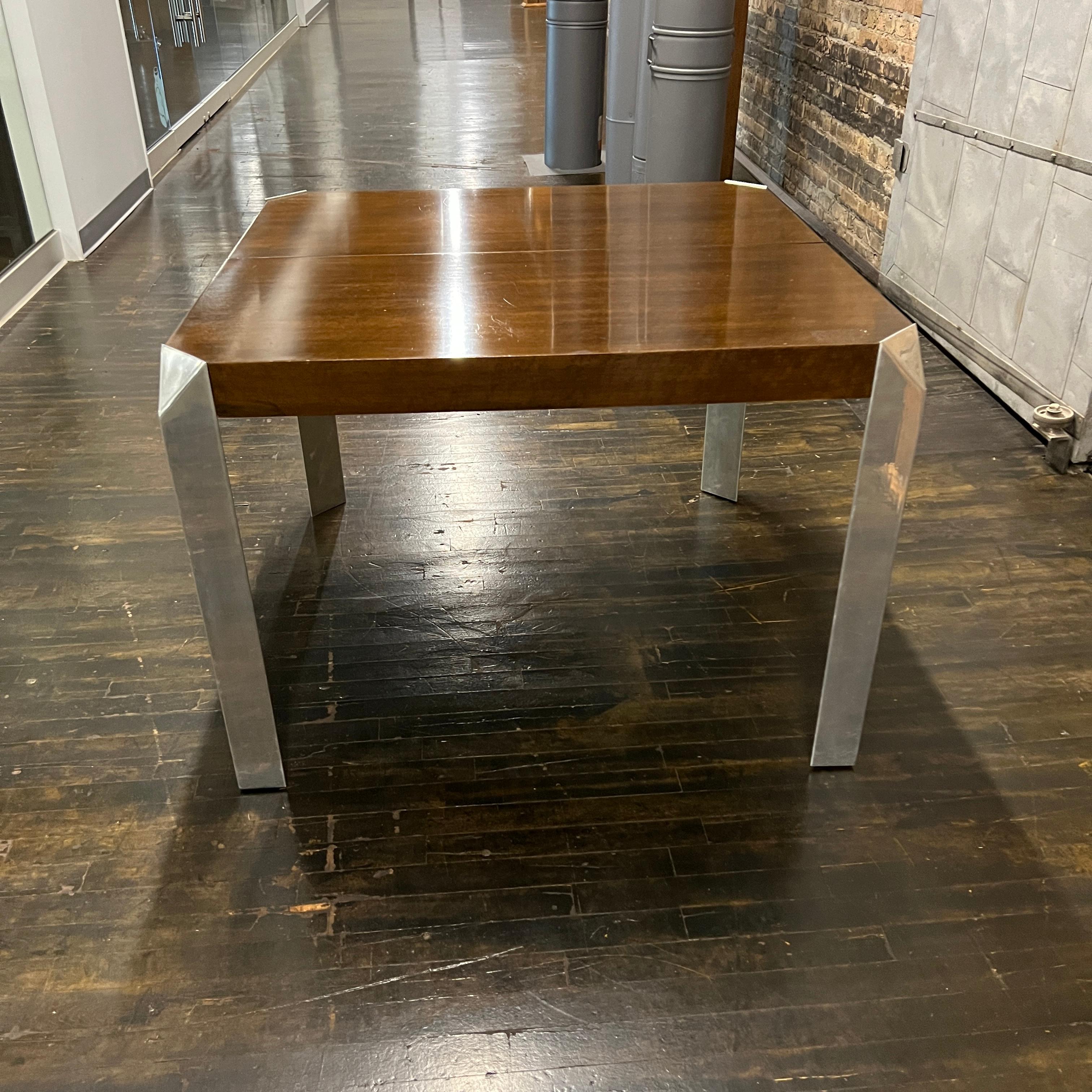 Stunning and unique mid-century dining table by Baker Furniture that features a rich brown wood top and triangular shaped polished chrome legs (that add an architectural element to the piece).  The table starts out as a square (40