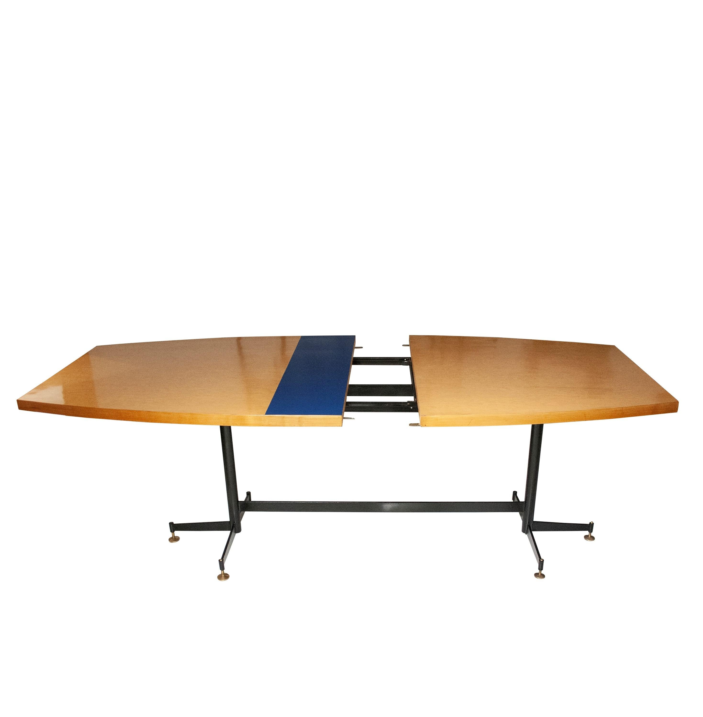 Extendable table designed by Luigi Scremin (1897-1983). Board made of birch wood with a blue laminated central detail. The base structure consists of black lacquered iron with adjustable bronze pad details. Extended lenght: 260cm. 