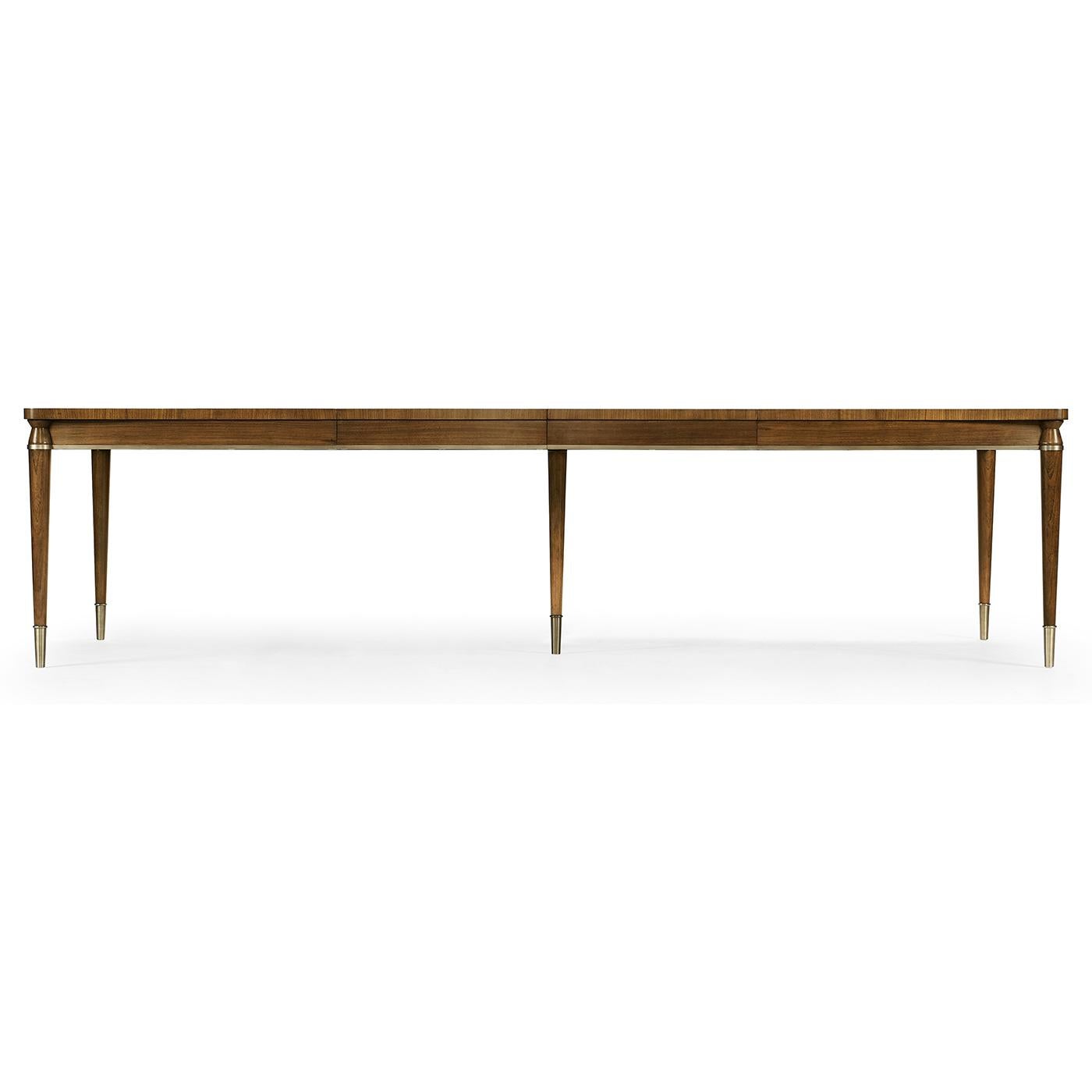 A Mid-Century Modern extending dining table with a crossbanded and figured walnut veneer in a book-matched pattern reminiscent of straw work with brass hardware and trim on turned and tapered legs also with brass caps.

Dimensions: 120