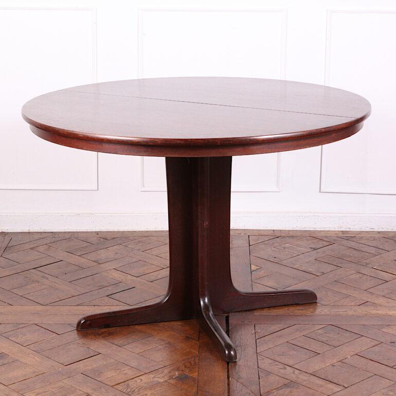 Extending round mahogany Mid-Century Modern ( MCM )dining table with two leaves, the simple pedestal base splitting into two sections when the table is extended. 
Dimensions shown below are the table closed; it measures 90