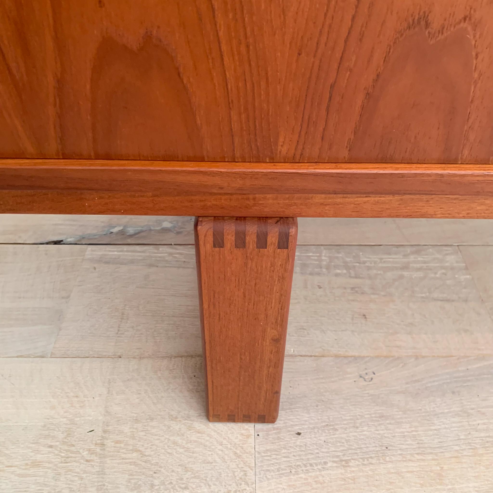 Transform your space with this stunning mid-century modern Danish teak credenza. Featuring sliding doors and adjustable shelving inside, this piece combines functionality with sleek design. The far left side includes convenient drawers, all of which